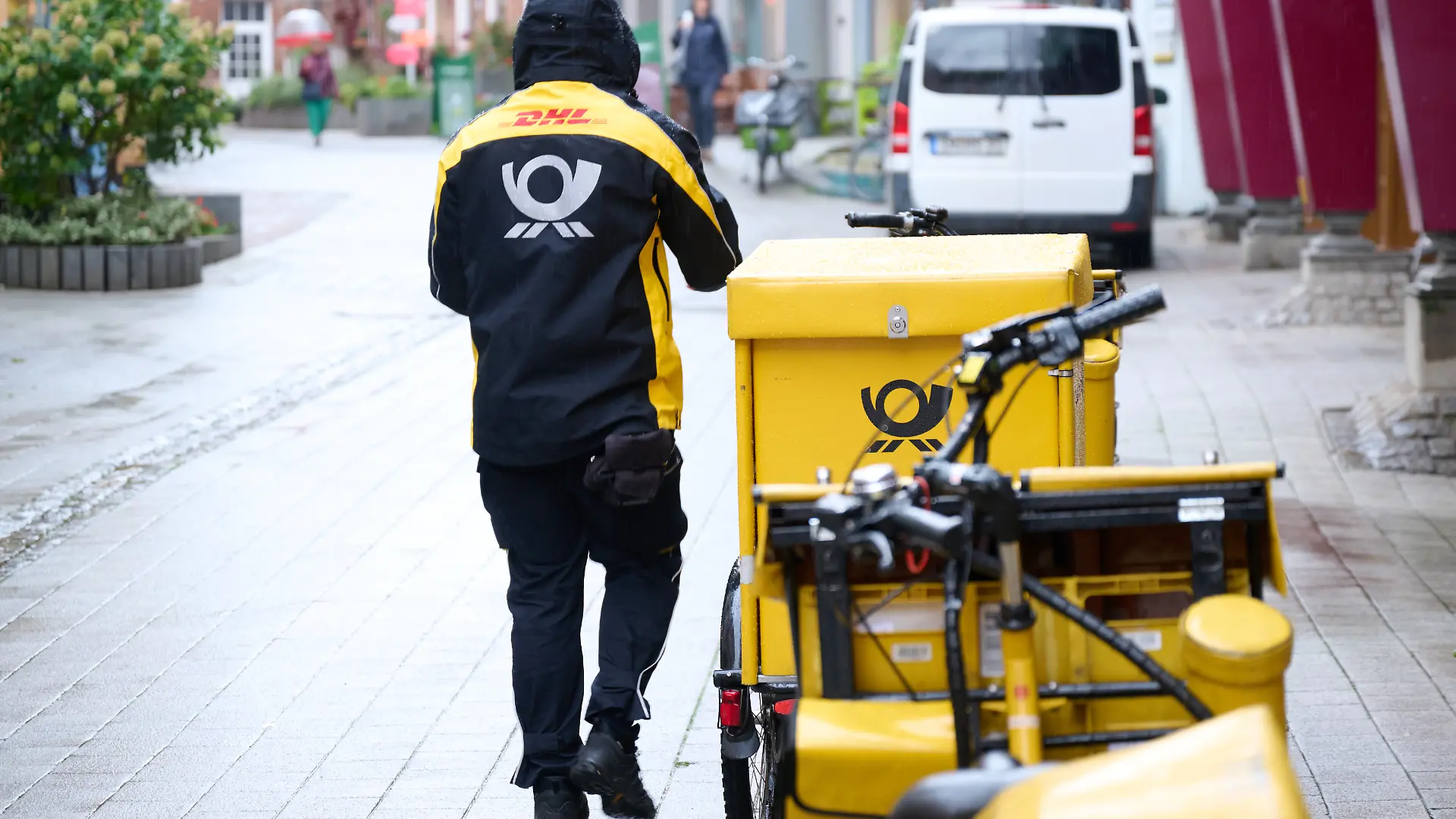 Ein Postbote stellt Briefe mit einem Postfahrrad zu.