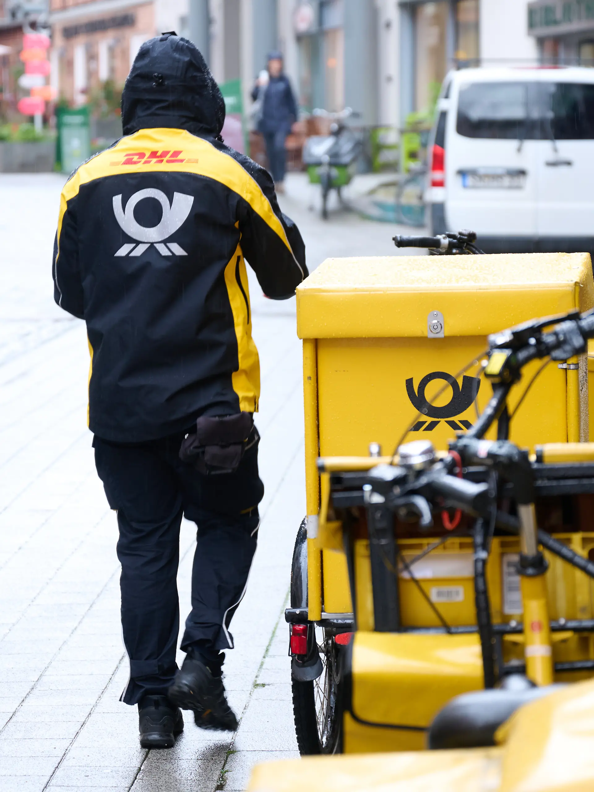 Ein Postbote stellt Briefe mit einem Postfahrrad zu.