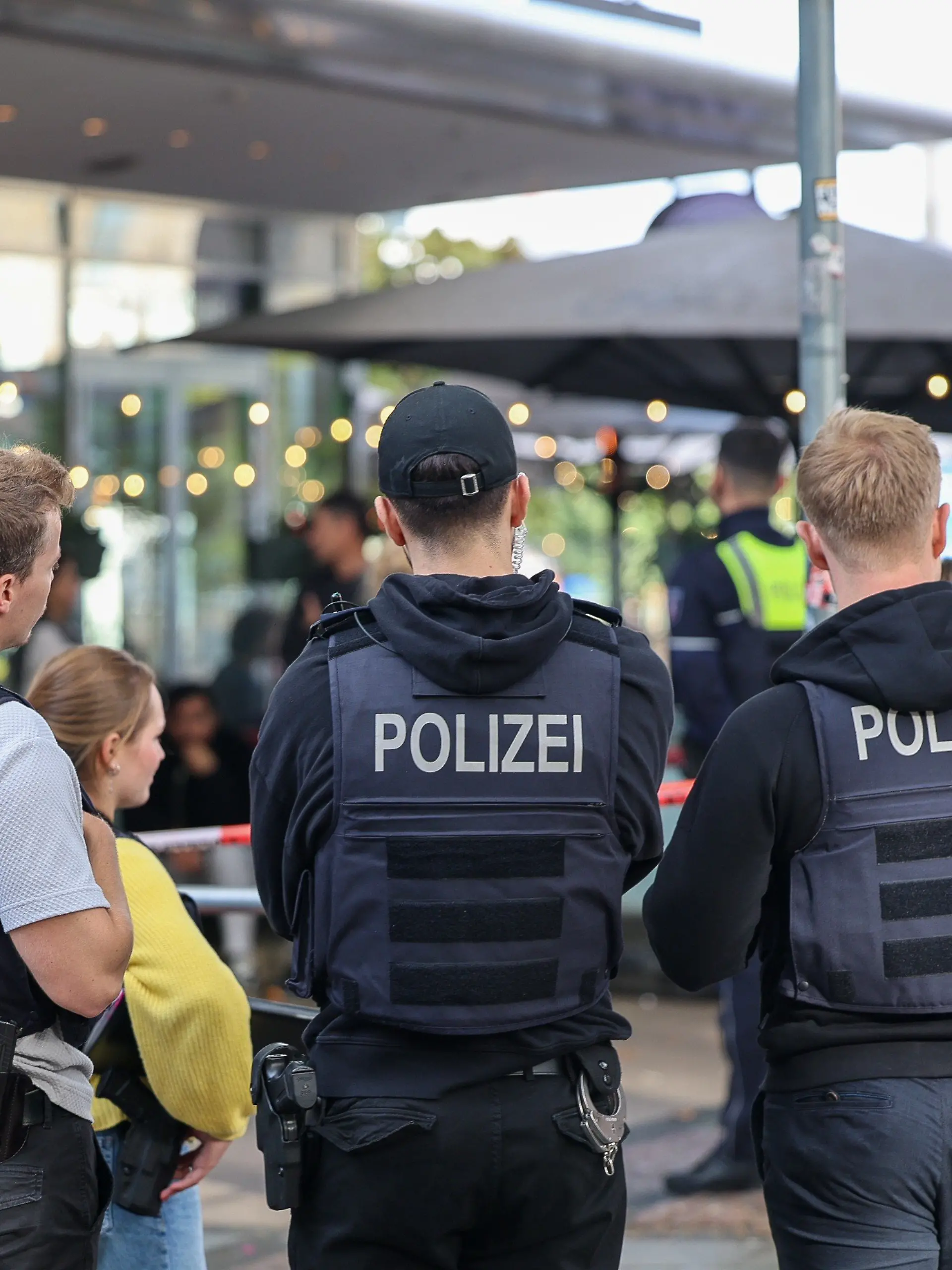14.10.2026, Nordrhein-Westfalen, Essen: Polizisten stehen vor einem Absperrband. Zwei Unbekannte haben mitten in Essen zwei Justizbeamte angegriffen und einen 34 Jahre alten Häftling befreit. Die beiden Justizbediensteten, die den Gefangenen in eine Arztpraxis bringen sollten, wurden nach Informationen der Deutschen Presse-Agentur überwältigt und gefesselt. Foto: Matthias Rosenkranz/dpa +++ dpa-Bildfunk +++