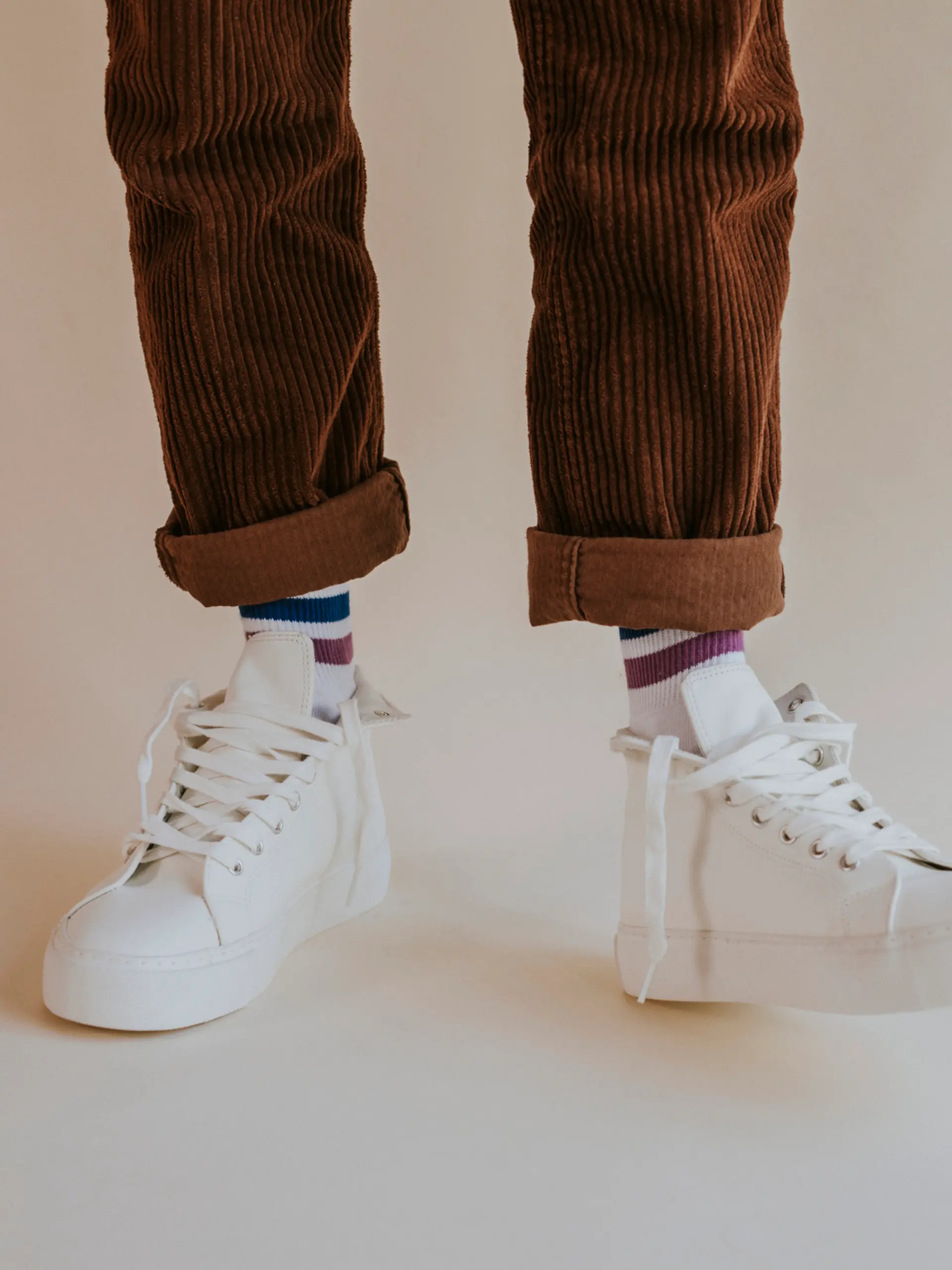 Ein Mann trägt eine braune Cordhose und weiße Sneaker.