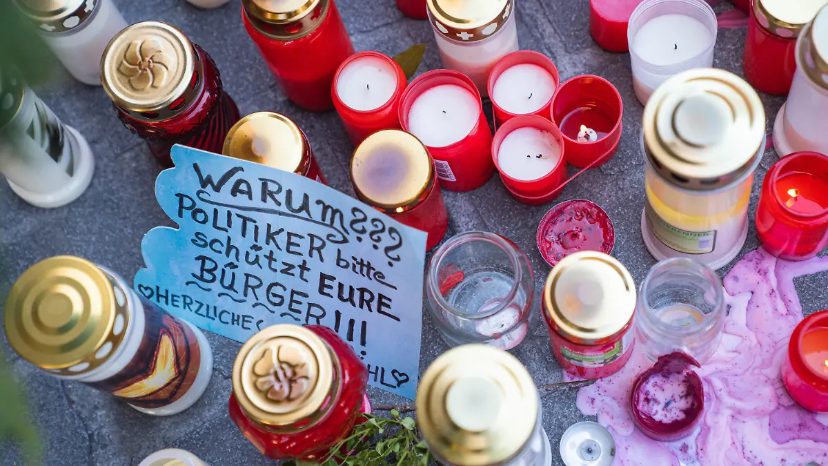 28.06.2021, Bayern, Würzburg: Ein Zettel mit der Aufschrift ·Warum??? Politiker bitte schützt Eure Bürger!!!· liegt neben Trauerkerzen und Blumen vor einem Kaufhaus in der Innenstadt, in dem ein Mann Menschen mit einem Messer attackiert hatte. Bei dem Angriff am 25.06.2021 hatte ein Somalier drei Frauen in einem Kaufhaus getötet. Auf der Straße und in einer nahen Bank verletzte er danach laut Polizei sechs Menschen schwer und einen leicht. Foto: Nicolas Armer/dpa +++ dpa-Bildfunk +++