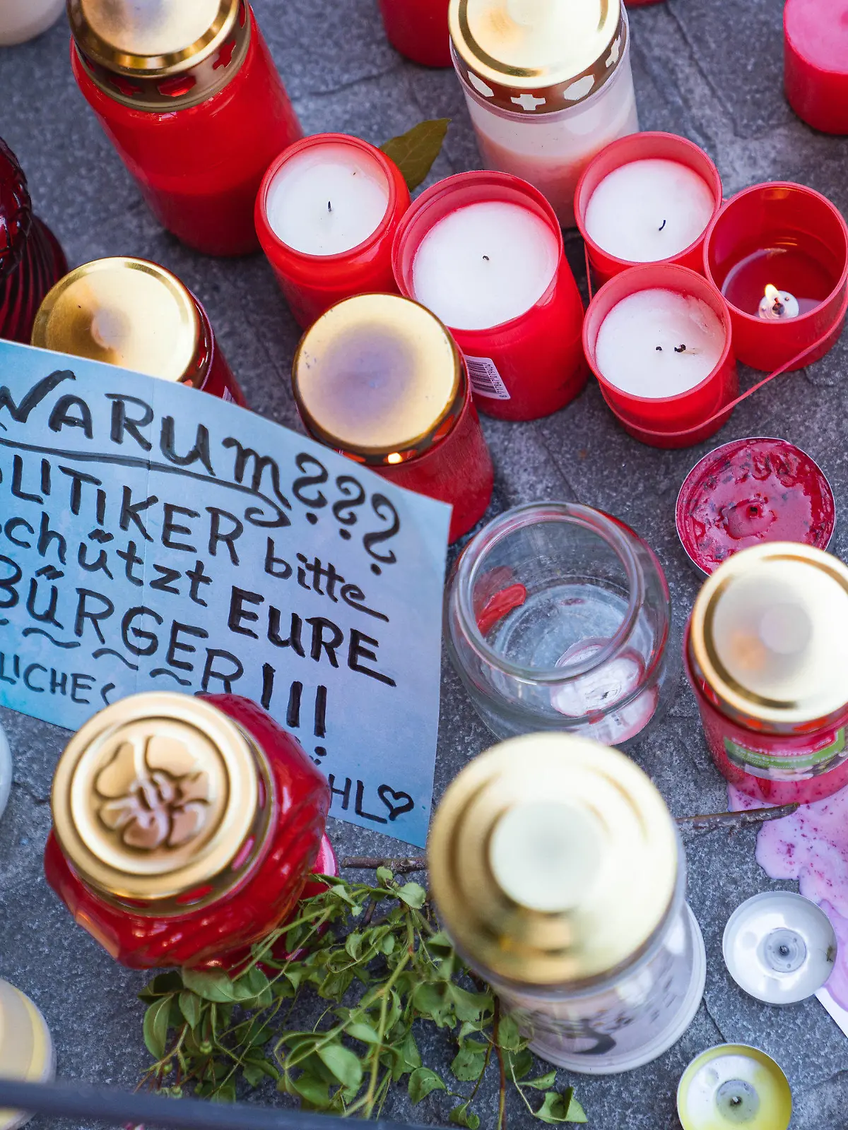 28.06.2021, Bayern, Würzburg: Ein Zettel mit der Aufschrift ·Warum??? Politiker bitte schützt Eure Bürger!!!· liegt neben Trauerkerzen und Blumen vor einem Kaufhaus in der Innenstadt, in dem ein Mann Menschen mit einem Messer attackiert hatte. Bei dem Angriff am 25.06.2021 hatte ein Somalier drei Frauen in einem Kaufhaus getötet. Auf der Straße und in einer nahen Bank verletzte er danach laut Polizei sechs Menschen schwer und einen leicht. Foto: Nicolas Armer/dpa +++ dpa-Bildfunk +++