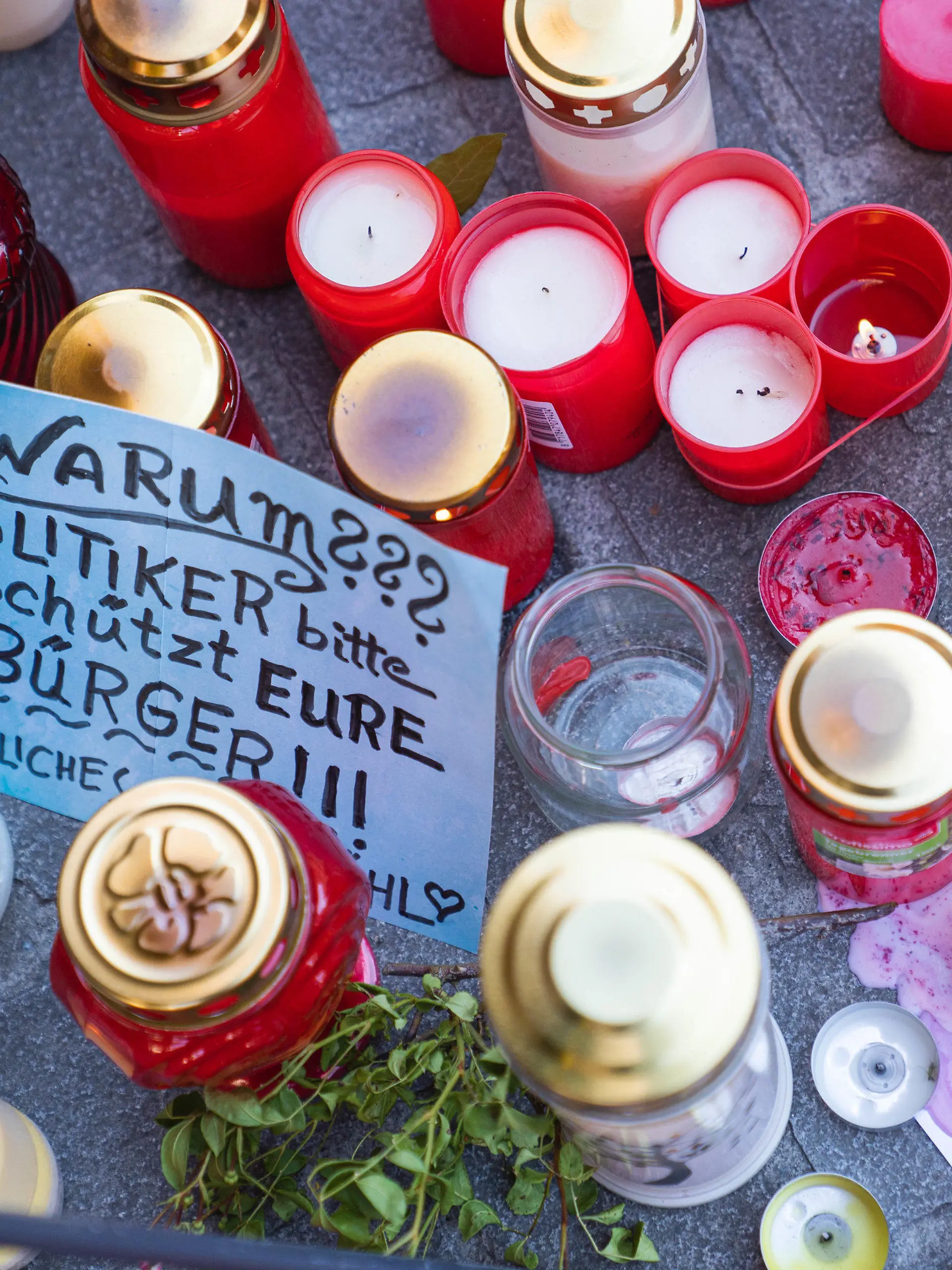 28.06.2021, Bayern, Würzburg: Ein Zettel mit der Aufschrift ·Warum??? Politiker bitte schützt Eure Bürger!!!· liegt neben Trauerkerzen und Blumen vor einem Kaufhaus in der Innenstadt, in dem ein Mann Menschen mit einem Messer attackiert hatte. Bei dem Angriff am 25.06.2021 hatte ein Somalier drei Frauen in einem Kaufhaus getötet. Auf der Straße und in einer nahen Bank verletzte er danach laut Polizei sechs Menschen schwer und einen leicht. Foto: Nicolas Armer/dpa +++ dpa-Bildfunk +++