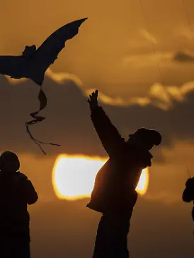 News Bilder des Tages Der Schattenriss von drei Personen zeichnet sich ab beim Drachensteigen vor Sonnenuntergang in Be