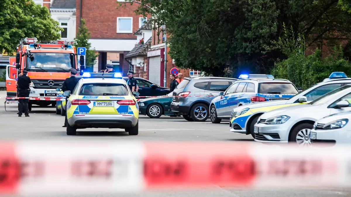 27.06.2019, Hamburg: Polizisten und Feuerwehrleute, stehen an einer abgesperrten Straße. Ein Mann ist in Hamburg-Lohbrügge am erschossen worden. Einzelheiten oder Hintergründe konnte ein Sprecher des Lagezentrums der Polizei zunächst nicht nennen. Foto: Daniel Bockwoldt/dpa +++ dpa-Bildfunk +++