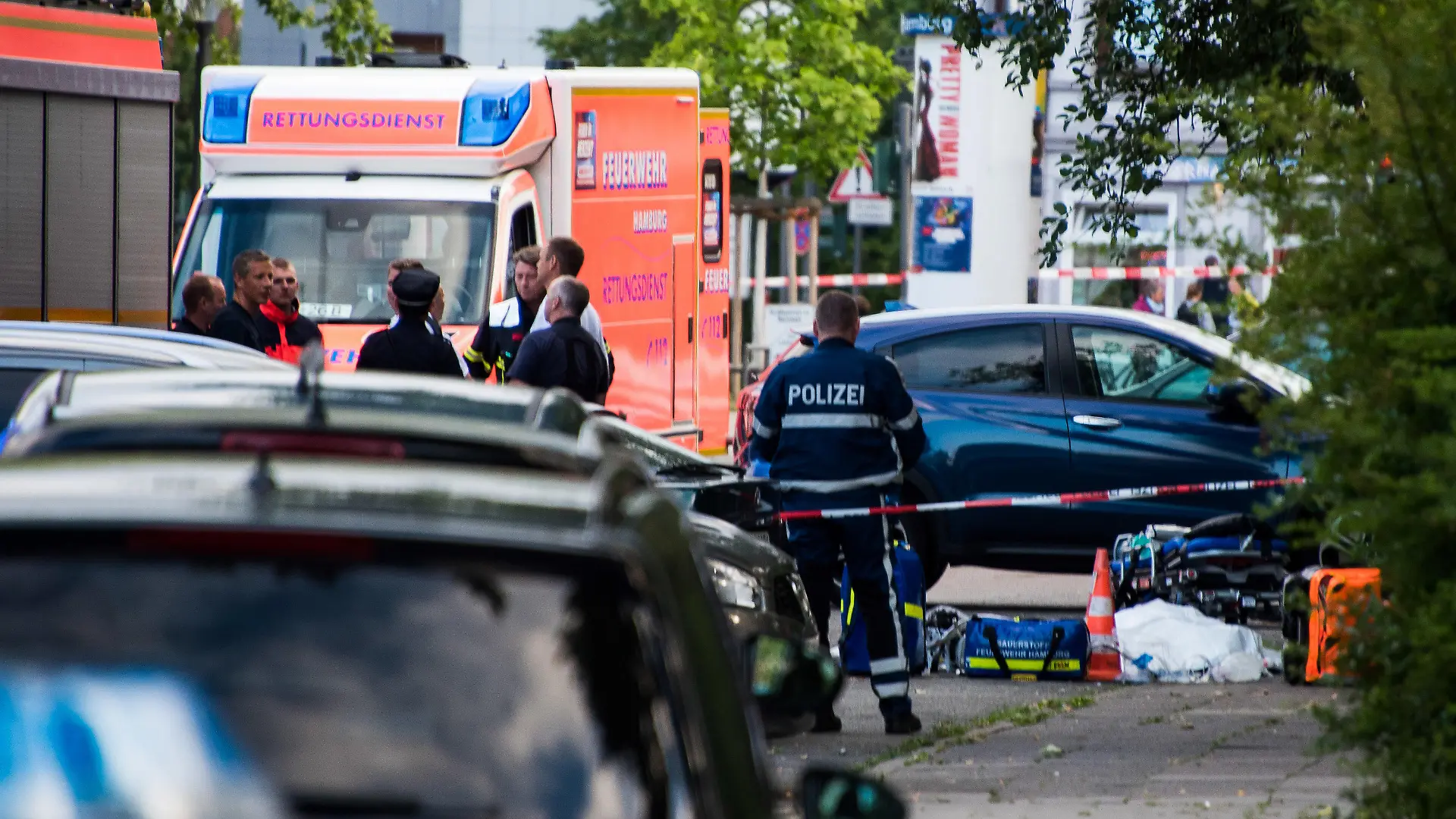 27.06.2019, Hamburg: Polizisten und Feuerwehrleute, stehen an einer abgesperrten Straße neben einem abgedeckten Körper. Ein Mann ist in Hamburg-Lohbrügge am erschossen worden. Einzelheiten oder Hintergründe konnte ein Sprecher des Lagezentrums der Polizei zunächst nicht nennen. Foto: Daniel Bockwoldt/dpa +++ dpa-Bildfunk +++
