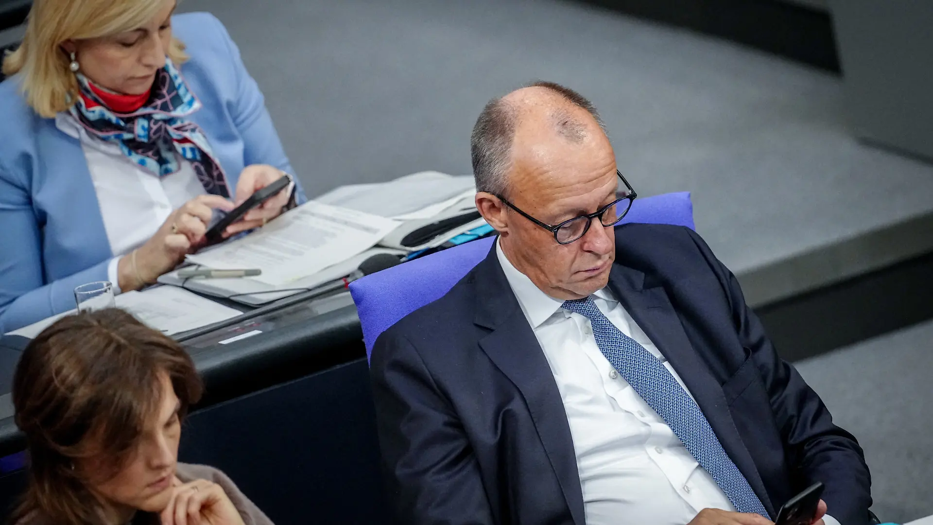 Nina Warken (CDU), Chefin des Bundeskanzleramts und Bundesministerin für besondere Aufgaben, und Bundeskanzler Friedrich Merz (CDU) schauen auf ihre Smartphones während der Sitzung des Bundestags.^Themen der Sitzung sind unter anderem Organspende und Befugnisse der deutschen Nachrichtendienste.