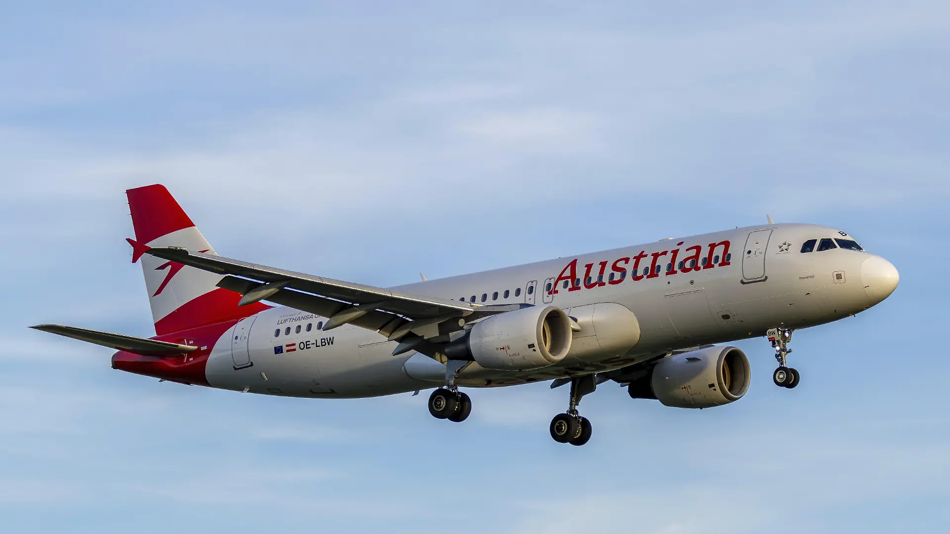 Ein Airbus A320 von Austrian Airlines mit dem Kennzeichen OE-LBW im seitlichen Landeanflug auf den Flughafen Stuttgart Die Maschine schwebt mit ausgefahrenem Fahrwerk vor blauem Himmel