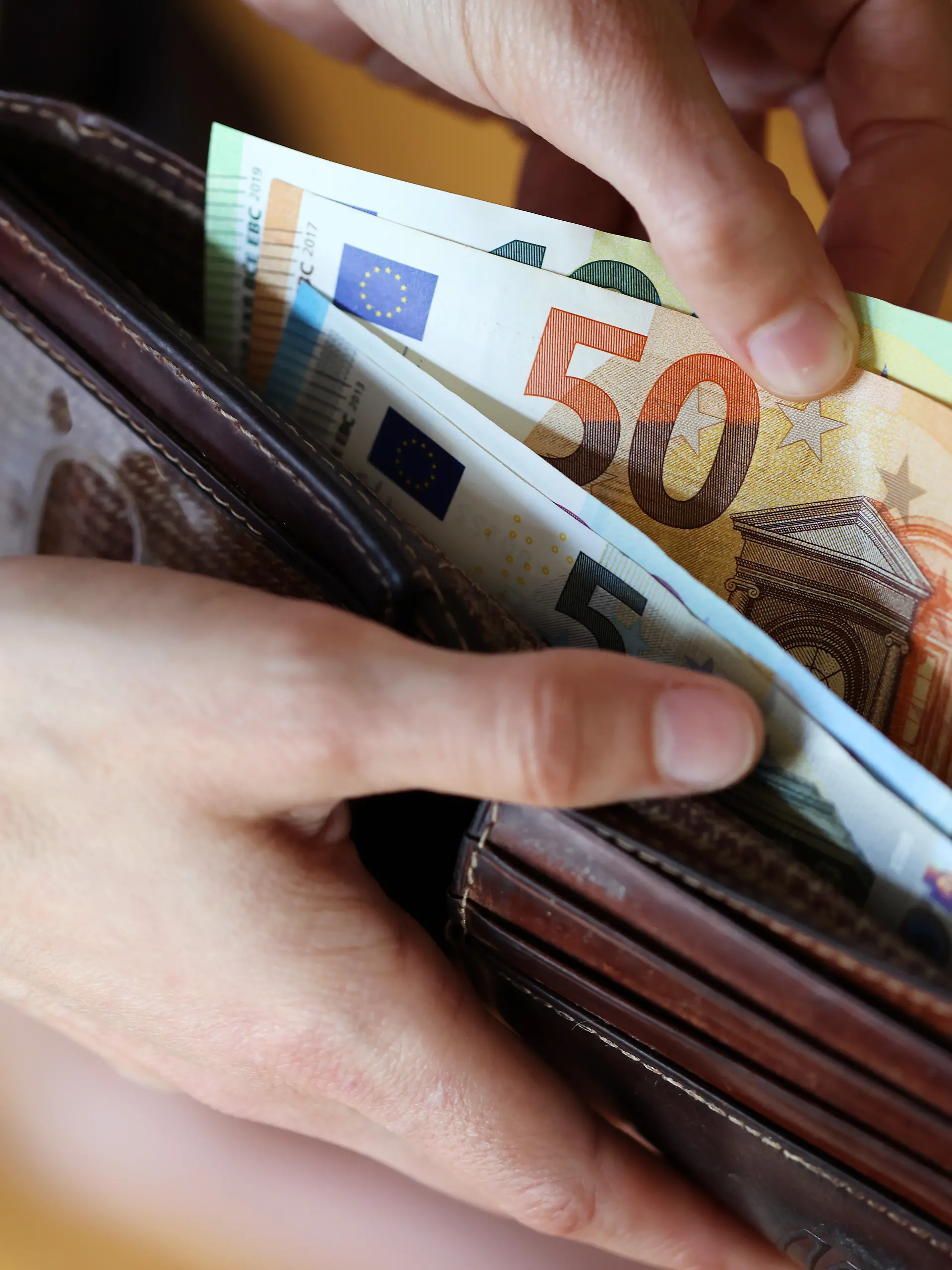 Geldscheine werden aus einem Porte­mon­naie entnommen.