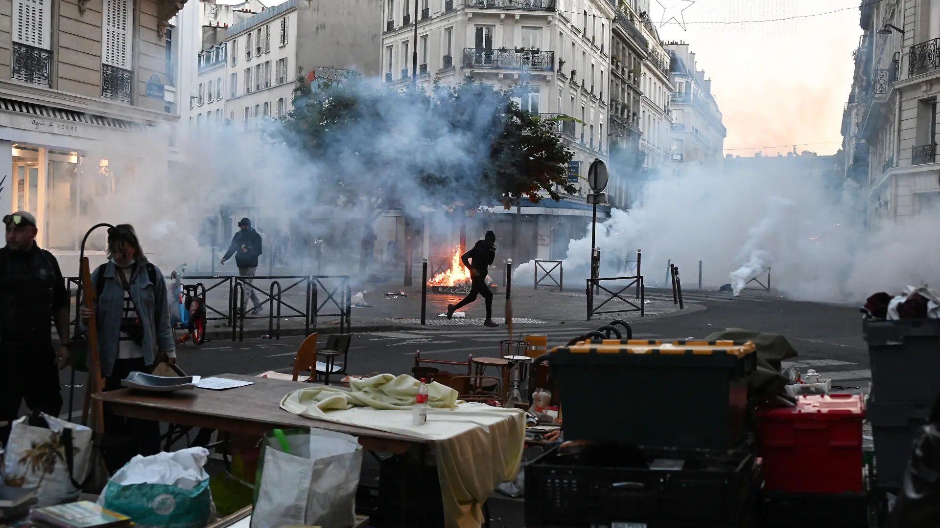 Ein Demonstrant rennt durch Tränengas, während es auf einem Flohmarkt erneut Zusammenstöße zwischen Demonstranten und Polizeibeamten in Paris dibt. +++ dpa-Bildfunk +++