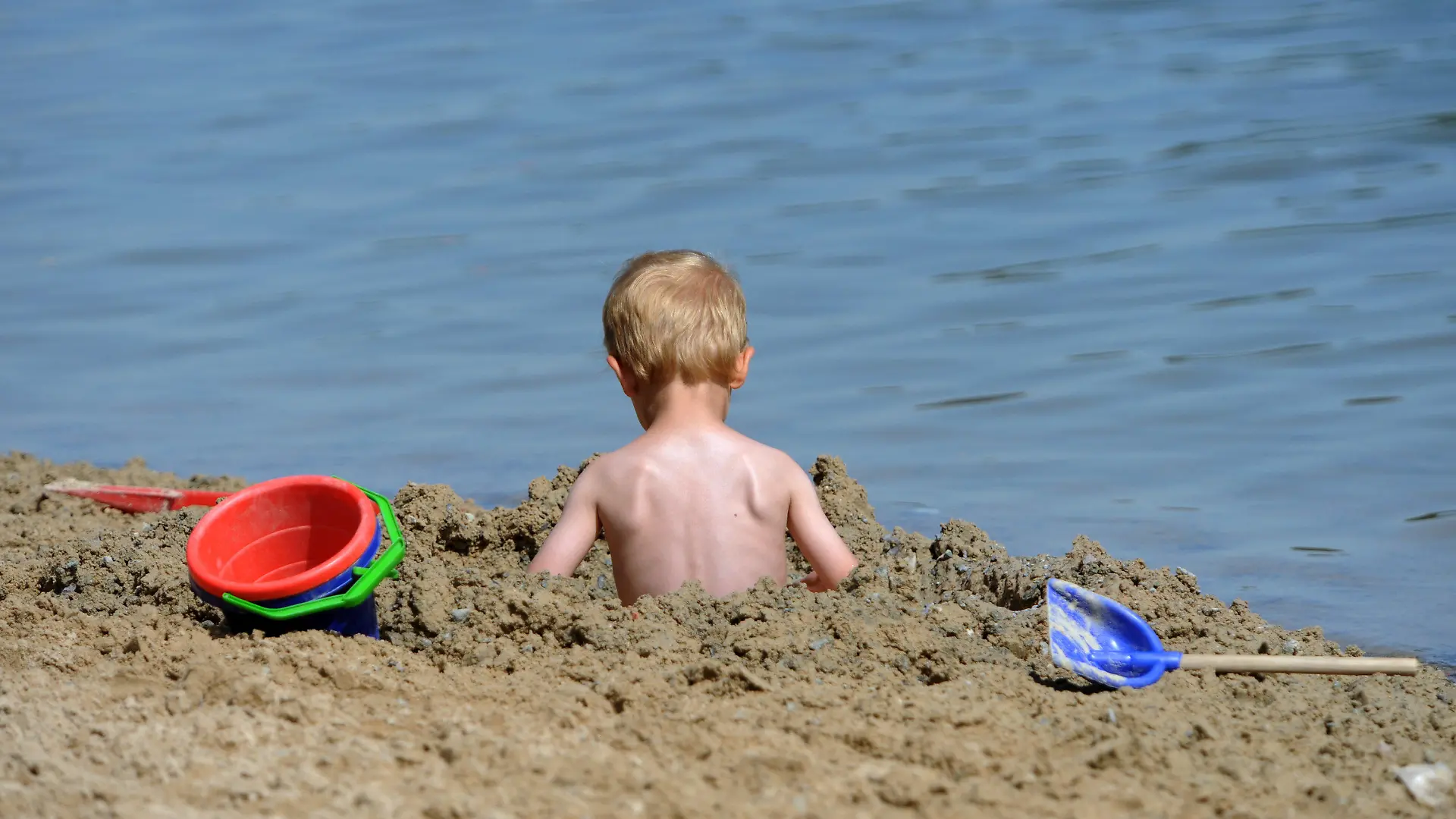 Ein kleines Kind sitzt am Freitag (17.08.2012) am Ufer des Twistesees bei Bad Arolsen (Landkreis Waldeck-Frankenberg) in einem Sandloch. Abkühlung wird sehr gefragt sein an diesem Wochenende, für das Rekordtemperaturen vorhergesagt wurden. Foto: Uwe Zucchi dpa/lhe  +++(c) dpa - Bildfunk+++