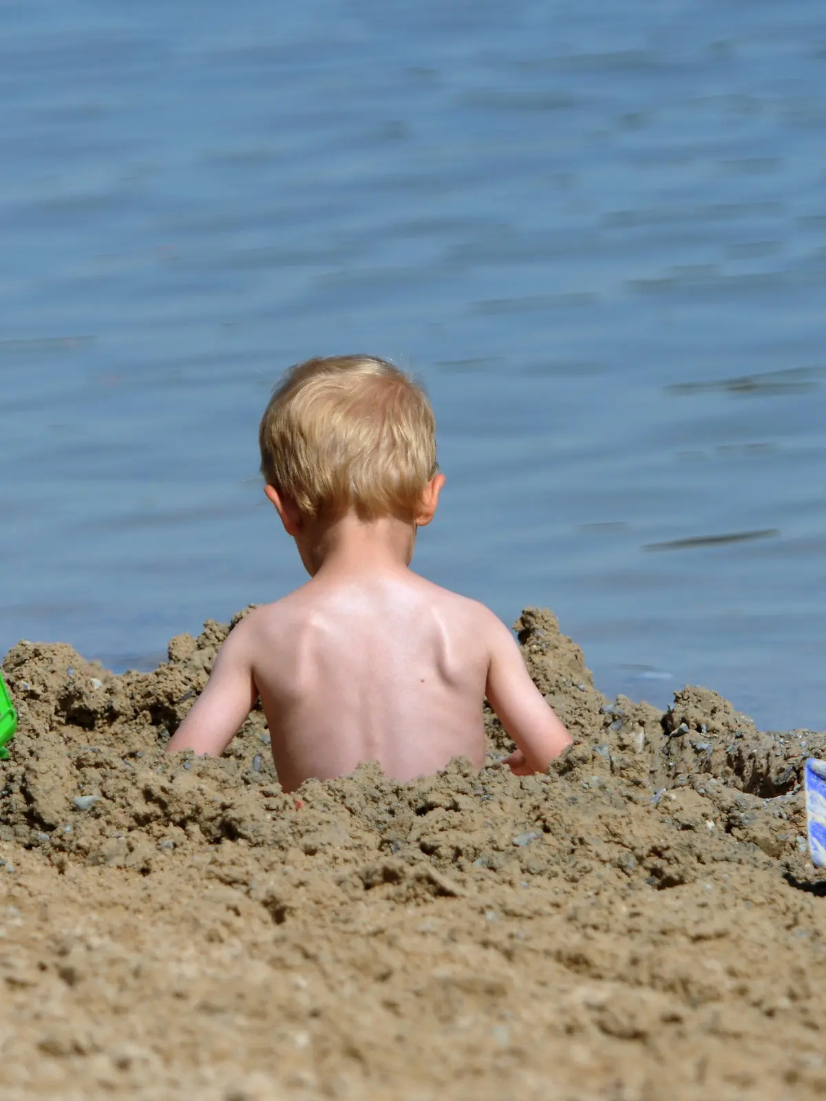 Ein kleines Kind sitzt am Freitag (17.08.2012) am Ufer des Twistesees bei Bad Arolsen (Landkreis Waldeck-Frankenberg) in einem Sandloch. Abkühlung wird sehr gefragt sein an diesem Wochenende, für das Rekordtemperaturen vorhergesagt wurden. Foto: Uwe Zucchi dpa/lhe  +++(c) dpa - Bildfunk+++