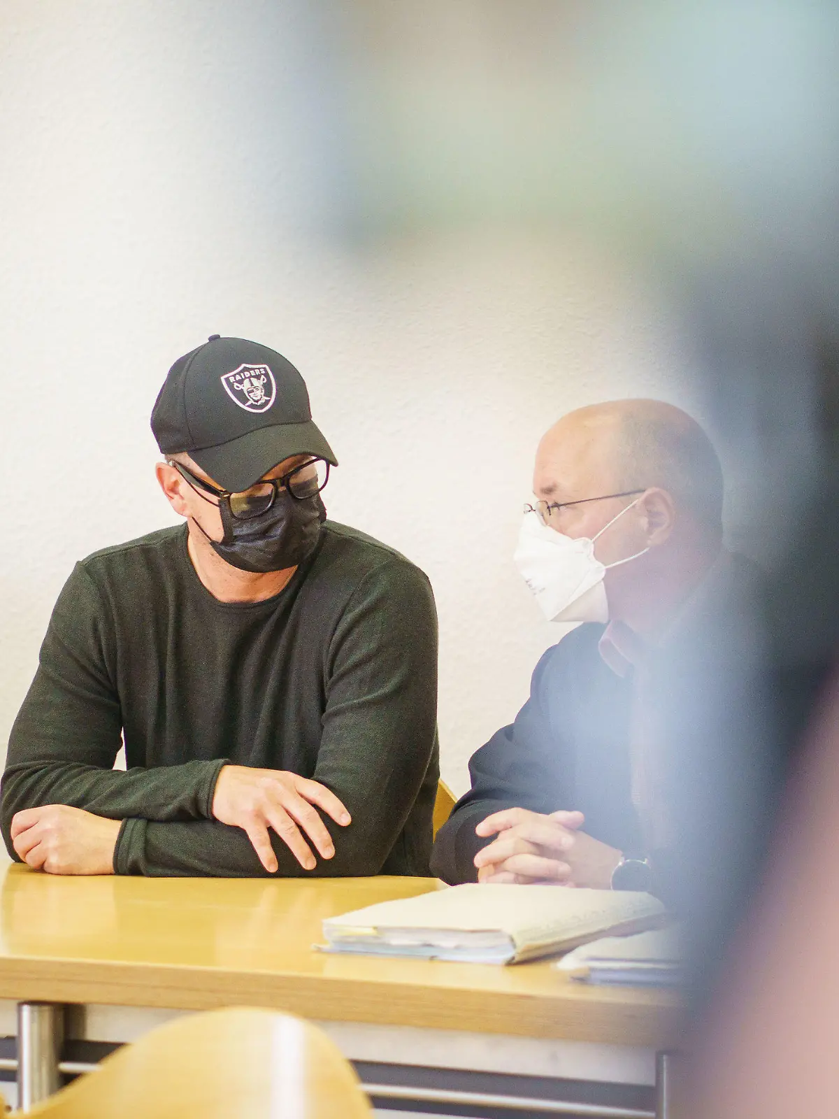 29.06.2021, Hessen, Alsfeld: Der angeklagte Polizeibeamte (l) sitzt im Amtsgericht neben seinem Verteidiger Ralf Lämmer. Dem 46-Jährigen wird zur Last gelegt, Ende 2018 "strafrechtlich relevante Inhalte" in WhatsApp-Gruppen versendet und damit auch eine mögliche Weiterverbreitung in Kauf genommen zu haben. Der Mann, der zuletzt im Polizeipräsidium Westhessen tätig war, war vom Dienst suspendiert worden. Foto: Frank Rumpenhorst/dpa +++ dpa-Bildfunk +++