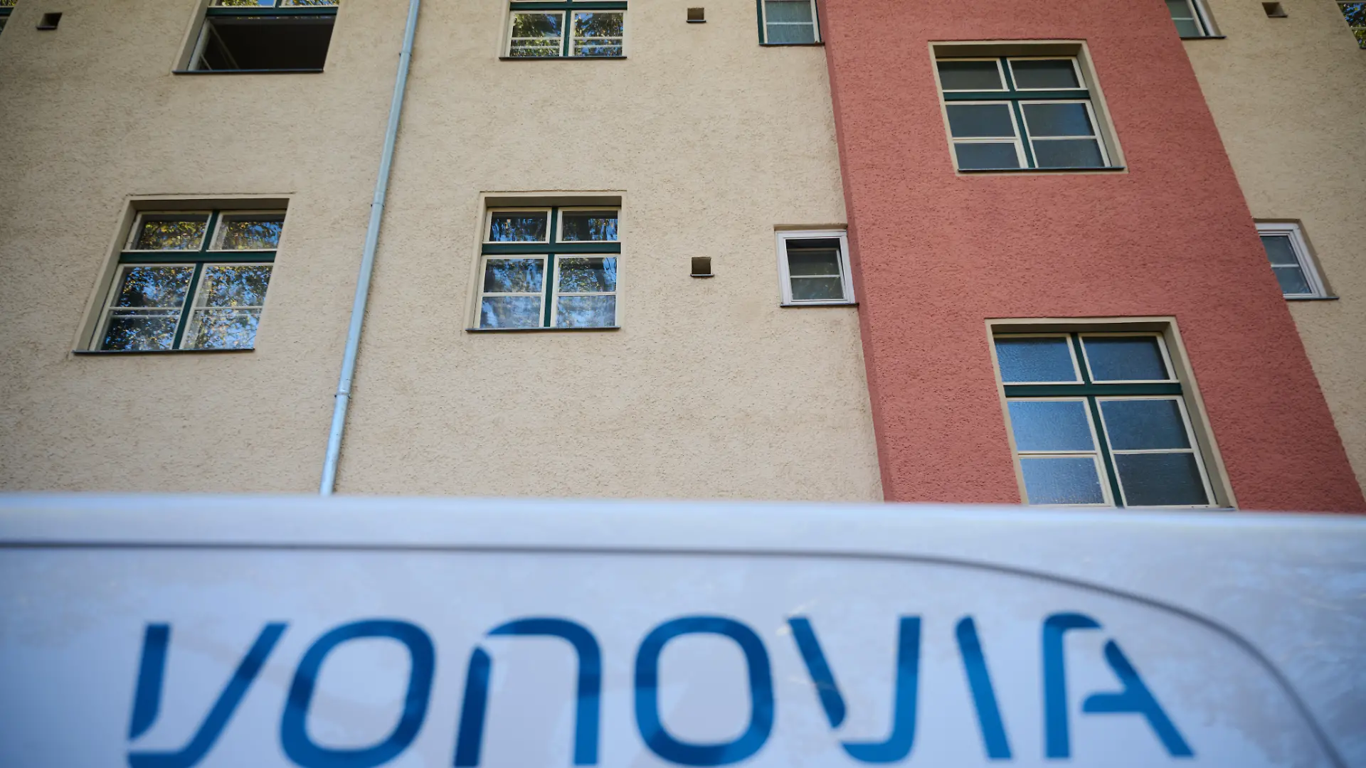 Ein Kastenwagen mit dem Schriftzug von Vonovia steht vor einem Mehrfamilienhaus.