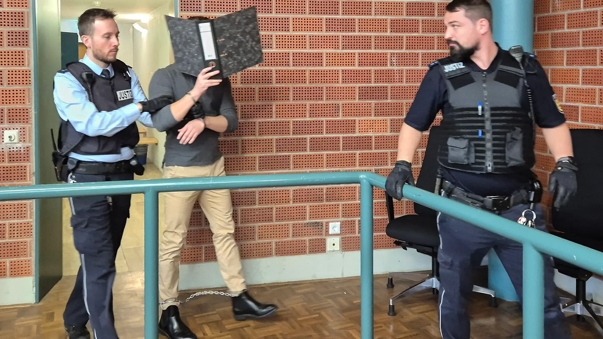 Ein Angeklagter wird zu seiner Verhandlung im Landgericht Konstanz geführt und verdeckt dabei sein Gesicht mit einem Aktenordner. Dem 28-Jährigen wird unter anderem Urkundenfälschung und gefährliche Körperverletzung vorgeworfen. Der Rettungssanitäter soll sich in einer Schönheits-Praxis als Arzt ausgegeben haben. +++ dpa-Bildfunk +++