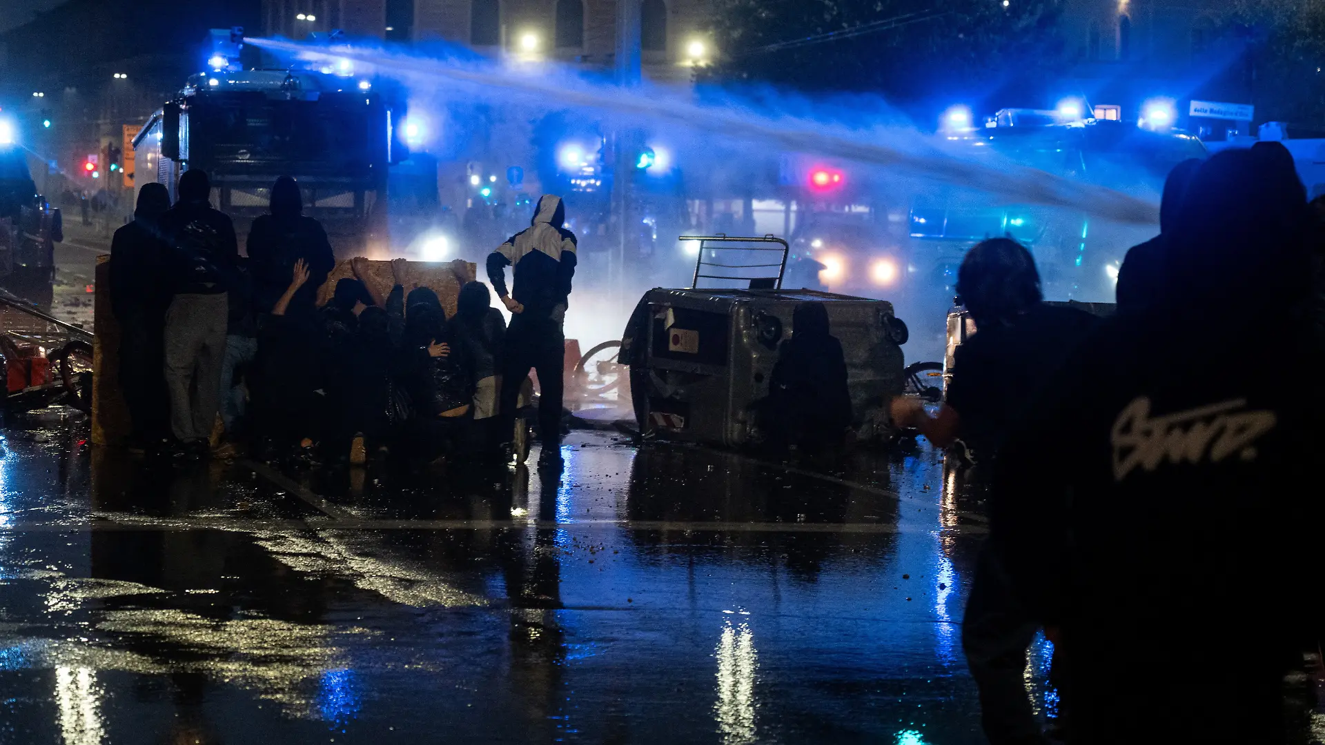 Police use a water cannon to disperse demonstrators sheltering behind makeshift barricades during clashes near the central railway station in Bologna, Italy, October 17, 2026. REUTERS/Michele Lapini