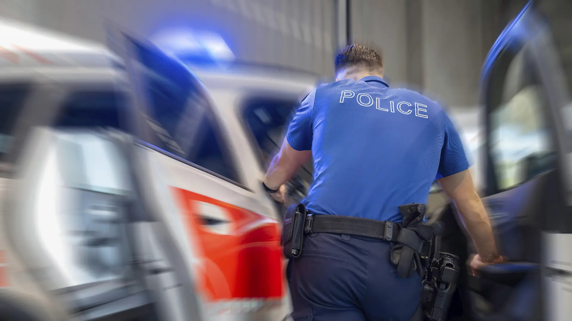 Ein Schweizer Polizist am Streifenwagen (Symbolbild)