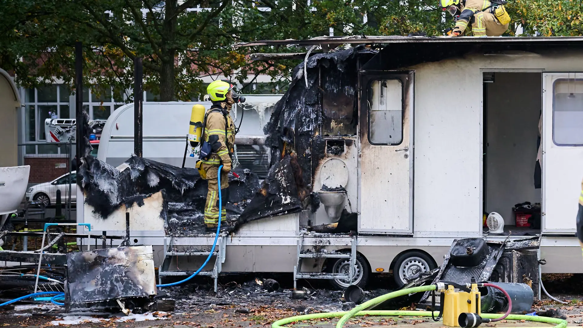 Einsatzkräfte der Feuerwehr stehen auf dem Bremer Freimarkt vor einem ausgebrannten Wohnanhänger. Die Besucherinnen und Besucher des Freimarkts waren nicht von dem Einsatz betroffen
