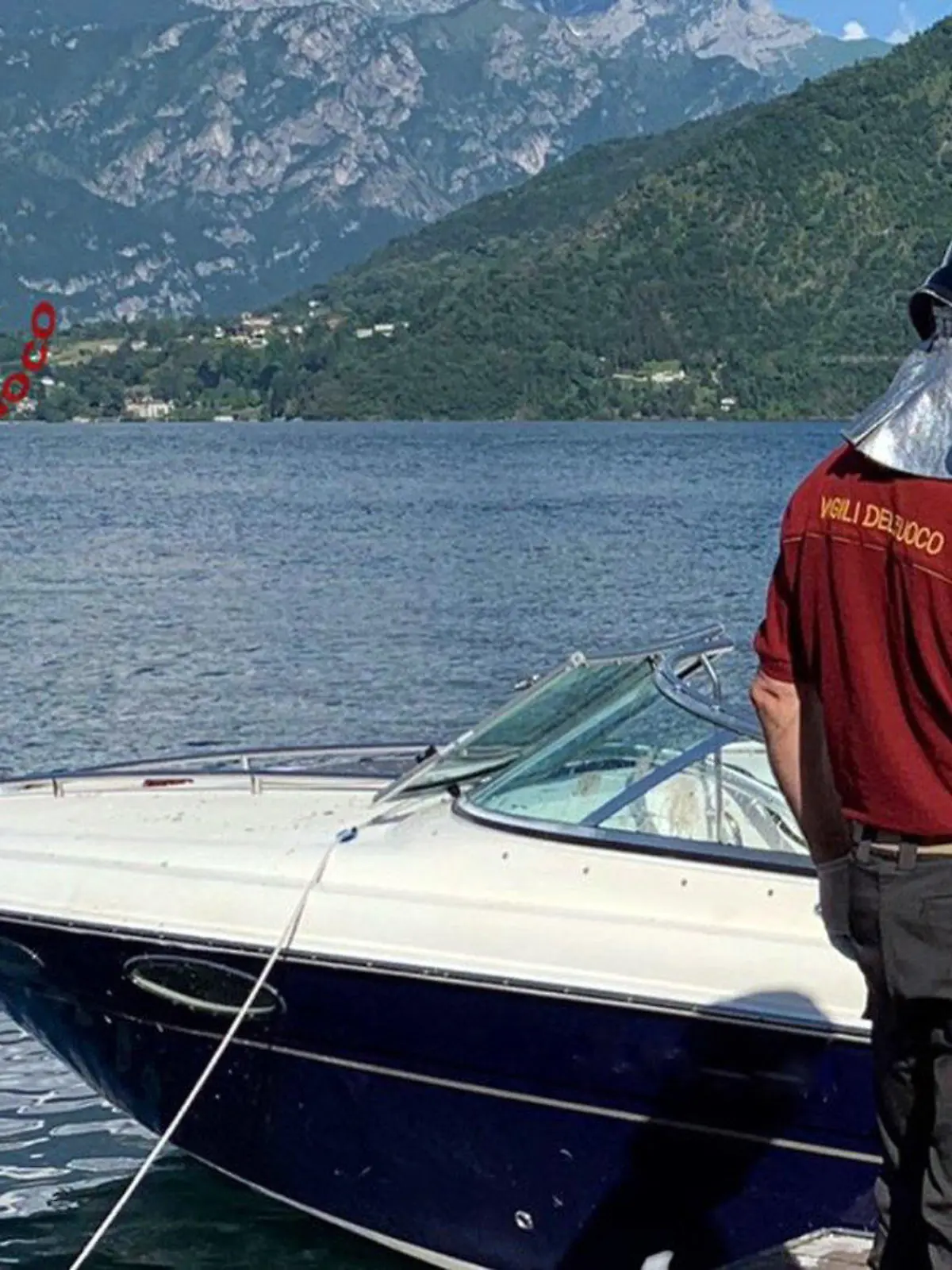HANDOUT - 26.06.2021, Italien, Lenno: Ein Feuerwehrmann steht neben einem Motorboot, das auf dem Comer See mit einem anderen Motorboot zusammengestoßen war. Dabei sei nach Angaben der Polizei ein 22 Jahre alter Italiener ums Leben gekommen, zwei weitere wurden verletzt. Eine abschließende Unglücksursache gebe es noch nicht. Foto: Vigilii Del Fuoco/dpa - ACHTUNG: Nur zur redaktionellen Verwendung im Zusammenhang mit der aktuellen Berichterstattung und nur mit vollständiger Nennung des vorstehenden Credits +++ dpa-Bildfunk +++