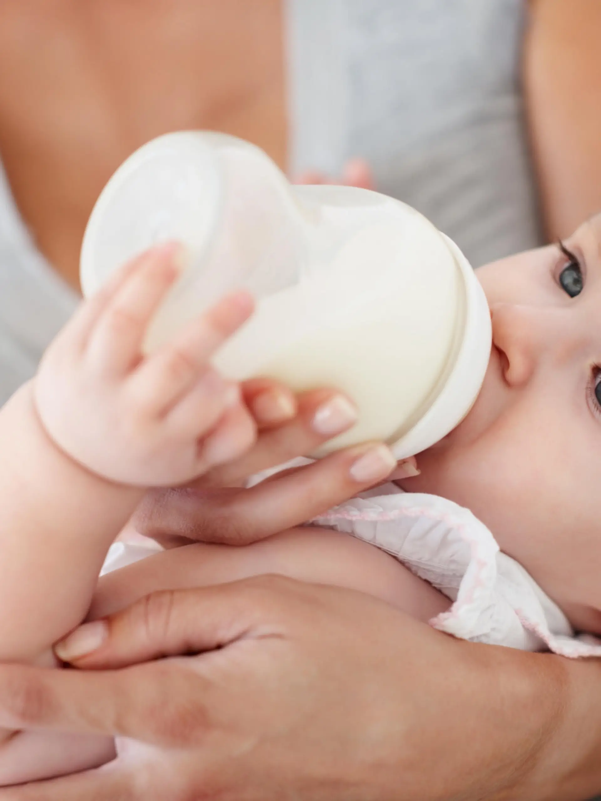Mutter füttert Kind mit Babymilch