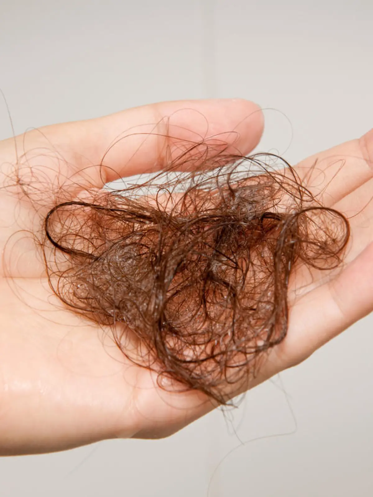 Woman holding up the hair she lost after washing them. Nikon D3X. Converted from RAW.