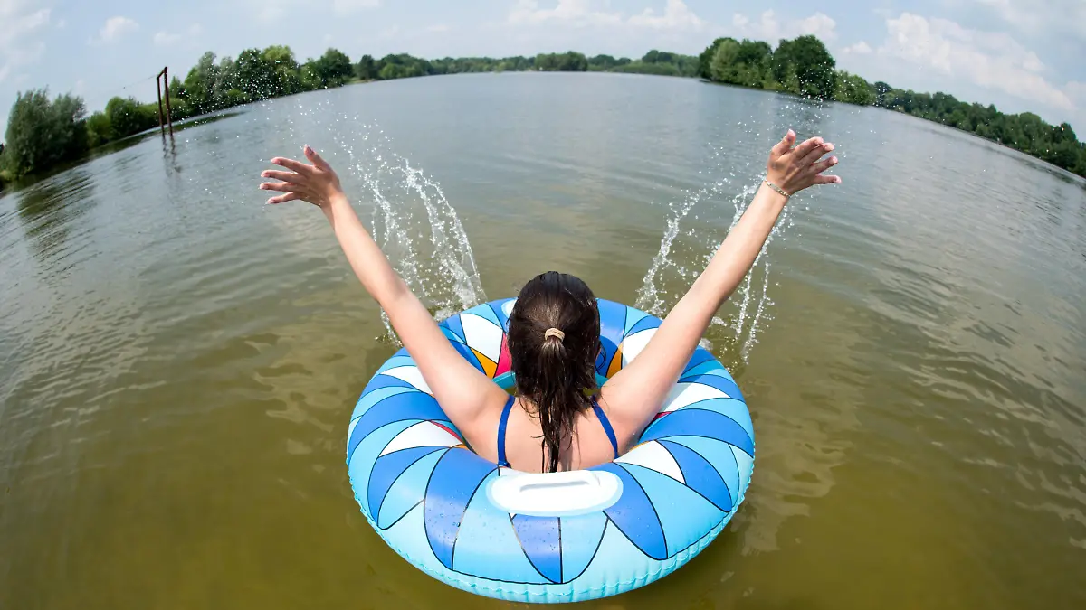 31.05.2018, Niedersachsen, Uetze: Ein junge Frau badet mit einem Schwimmreifen im Irenensee (Aufnahme mit Fisheye-Objektiv). Foto: Hauke-Christian Dittrich/dpa | Verwendung weltweit
