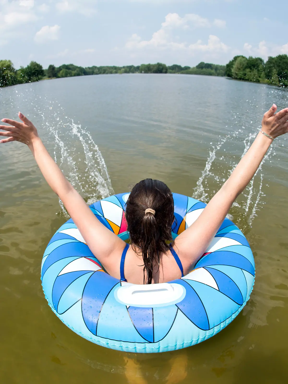 31.05.2018, Niedersachsen, Uetze: Ein junge Frau badet mit einem Schwimmreifen im Irenensee (Aufnahme mit Fisheye-Objektiv). Foto: Hauke-Christian Dittrich/dpa | Verwendung weltweit