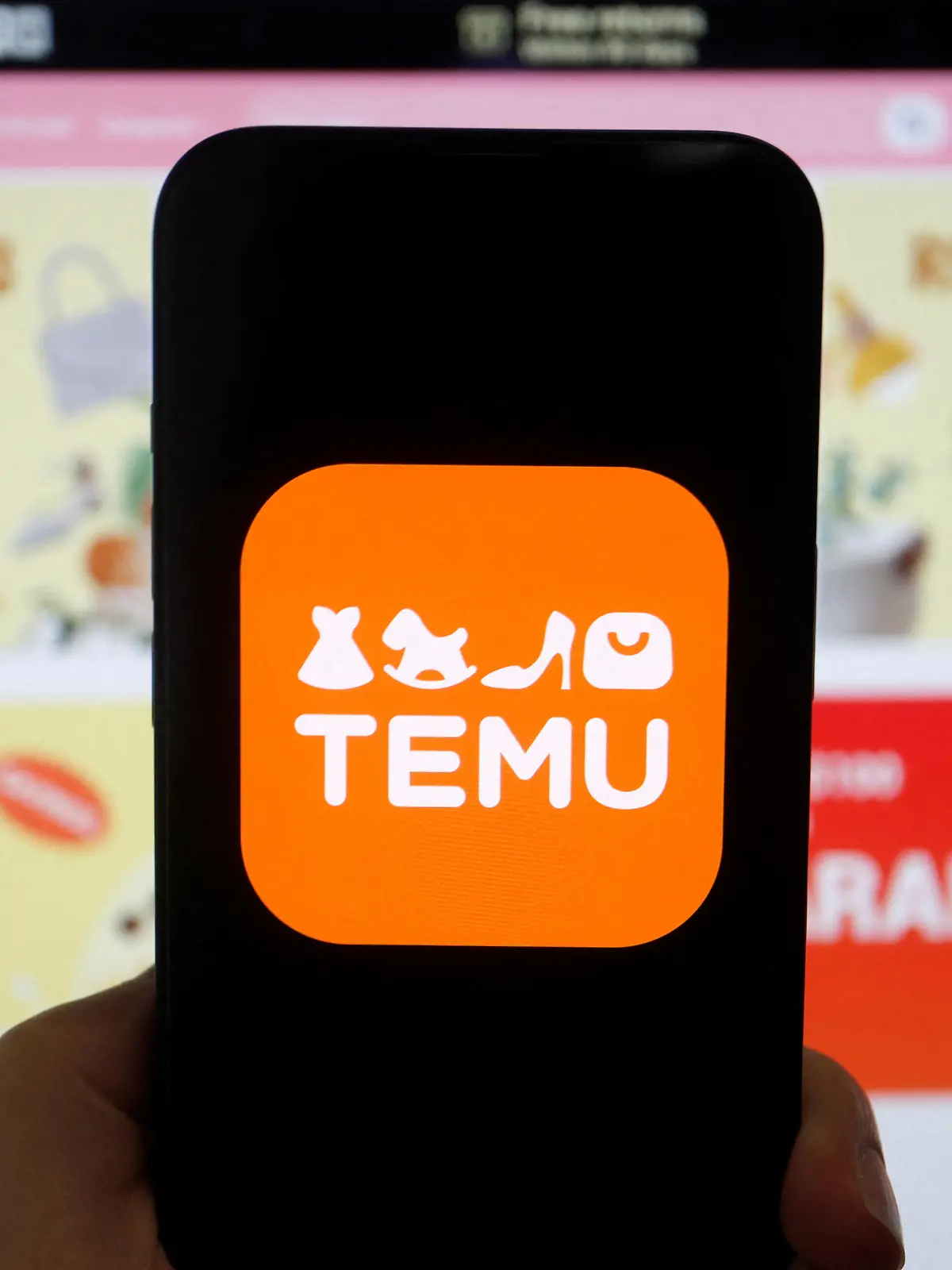 The logo of Temu, an e-commerce platform owned by PDD Holdings, is seen on a mobile phone displayed in front of its website, in this illustration picture taken April 26, 2023. REUTERS/Florence Lo/Illustration