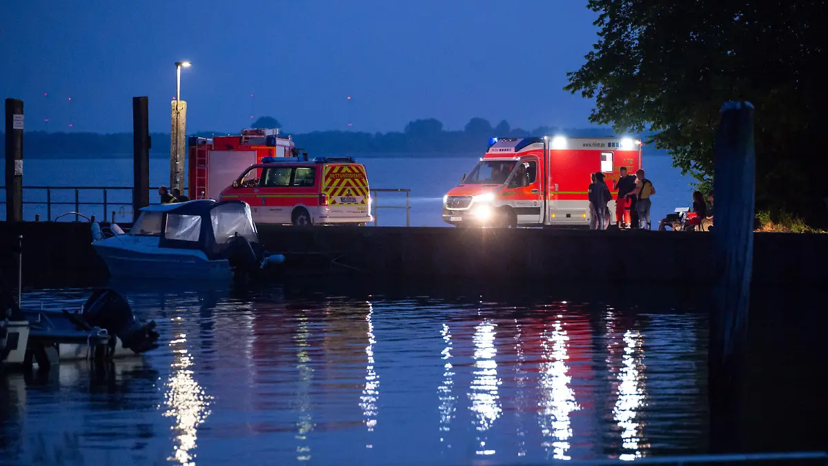 19.06.2021, Schleswig-Holstein, Kollmar: Trotz Dunkelheit stehen Einsatzkräfte am Anleger und suchen weiter nach dem vermissten Mädchen. In der Elbe bei Kollmar (Kreis Steinburg) suchen Einsatzkräfte nach einem siebenjährigen Mädchen, das dort baden gegangen war. Nach aktuellem Stand werde auch ein Erwachsener vermisst, sagte ein Sprecher der Feuerwehr am Samstagabend. Foto: Jonas Walzberg/dpa +++ dpa-Bildfunk +++
