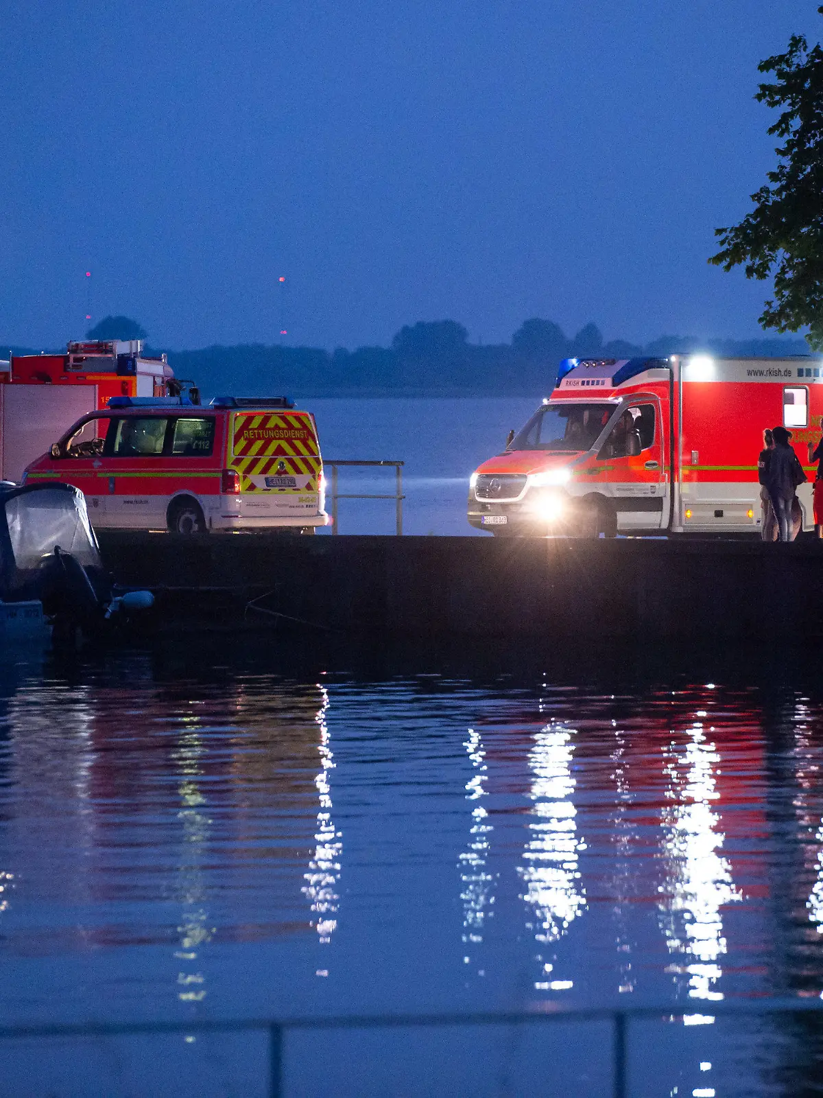 19.06.2021, Schleswig-Holstein, Kollmar: Trotz Dunkelheit stehen Einsatzkräfte am Anleger und suchen weiter nach dem vermissten Mädchen. In der Elbe bei Kollmar (Kreis Steinburg) suchen Einsatzkräfte nach einem siebenjährigen Mädchen, das dort baden gegangen war. Nach aktuellem Stand werde auch ein Erwachsener vermisst, sagte ein Sprecher der Feuerwehr am Samstagabend. Foto: Jonas Walzberg/dpa +++ dpa-Bildfunk +++