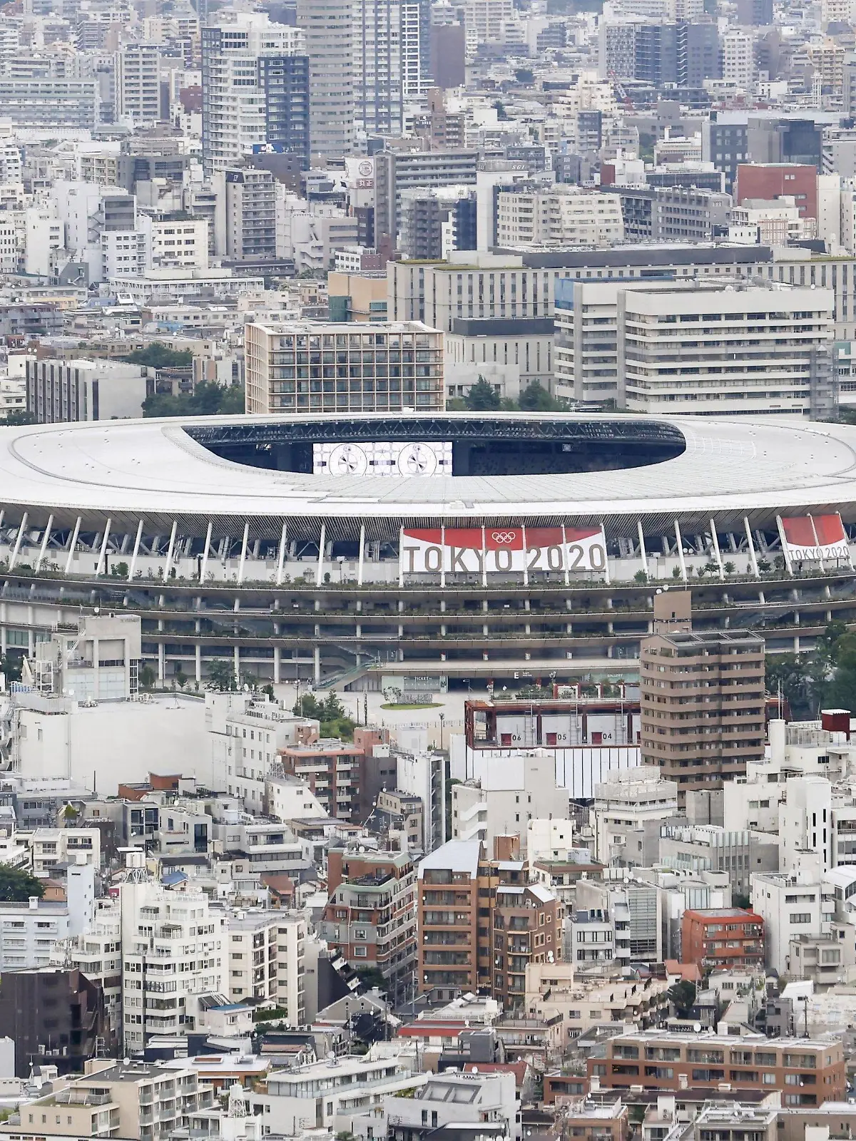 22.06.2021, Japan, Tokio: Ein Banner verkündet auf dem Nationalstadion, einem Austragungsort der Olympischen Spiele und Paralympics in Tokio, unter dem Zeichen der Olympischen Ringe "Tokio 2020". Die Olympischen Spiele 2020 sind die aktuellen Olympischen Sommerspiele und sollen corona-bedingt vom 23. Juli bis zum 8. August 2021 in Tokio stattfinden. Foto: ---/kyodo/dpa +++ dpa-Bildfunk +++