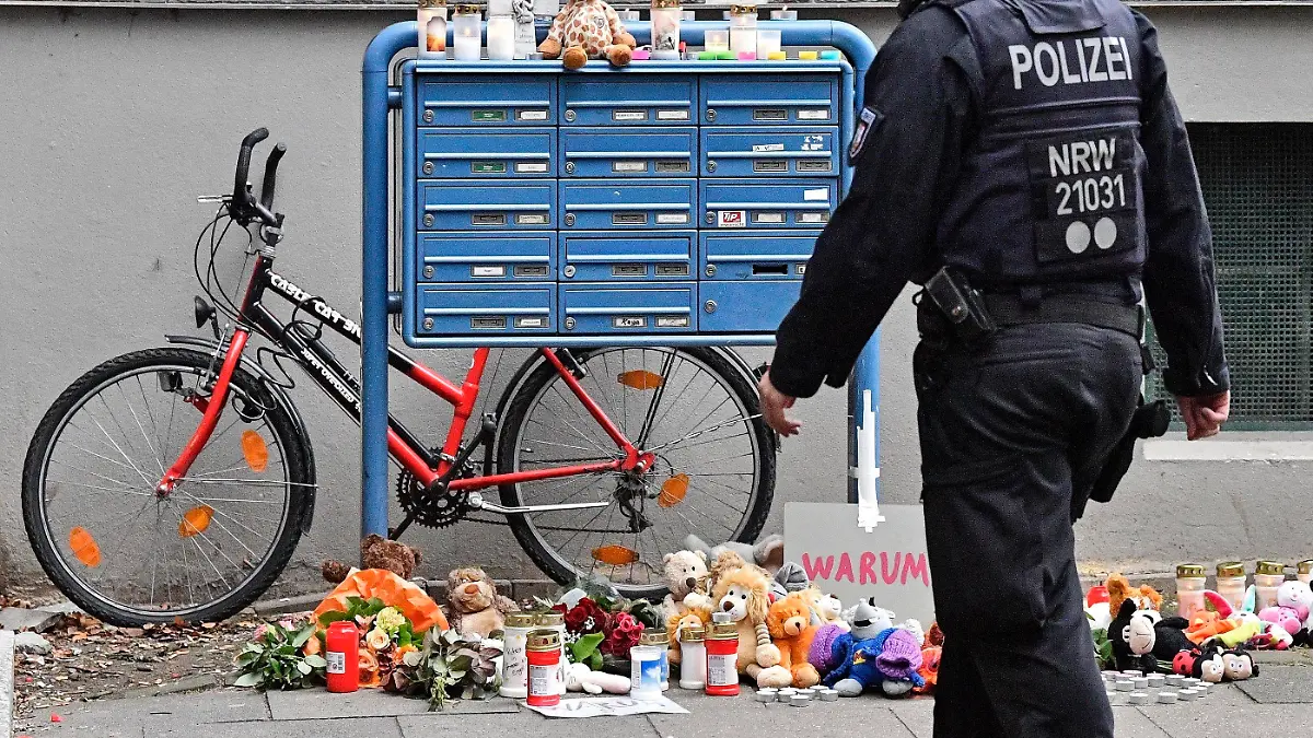 Police passes candles and teddy bears at the entrance of a house where five dead children were found in Solingen, Germany, Friday, Sept. 4, 2020. Police say five young children have been found dead on Thursday at the apartment in Solingen, their mother is suspected of killing them. Police said the children's 27-year-old mother later jumped in front of a train in Duesseldorf and was taken to a hospital with injuries. Only one child of the mother survived, who was send to his grandmother before. (AP Photo/Martin Meissner)