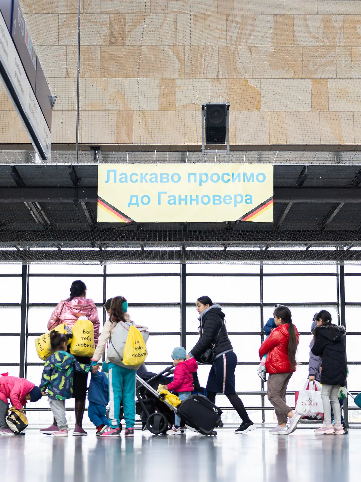 ARCHIV - 15.04.2023, Niedersachsen, Laatzen: Geflüchtete aus der Ukraine gehen durch die Eingangshalle vom Messebahnhof Laatzen. Auf einem Banner im Hintergrund steht «Willkommen in Hannover» auf Ukrainisch. Die Landeshauptstadt Hannover, die Städte Oldenburg und Osnabrück sowie die Landkreise Göttingen, Heidekreis, Uelzen und Osnabrück müssen demnach in dieser Zeit nur noch in Ausnahmefällen weitere Flüchtlinge aufnehmen. (zu dpa «Sieben Regionen müssen fast keine Flüchtlinge mehr aufnehmen») Foto: Michael Matthey/dpa +++ dpa-Bildfunk +++