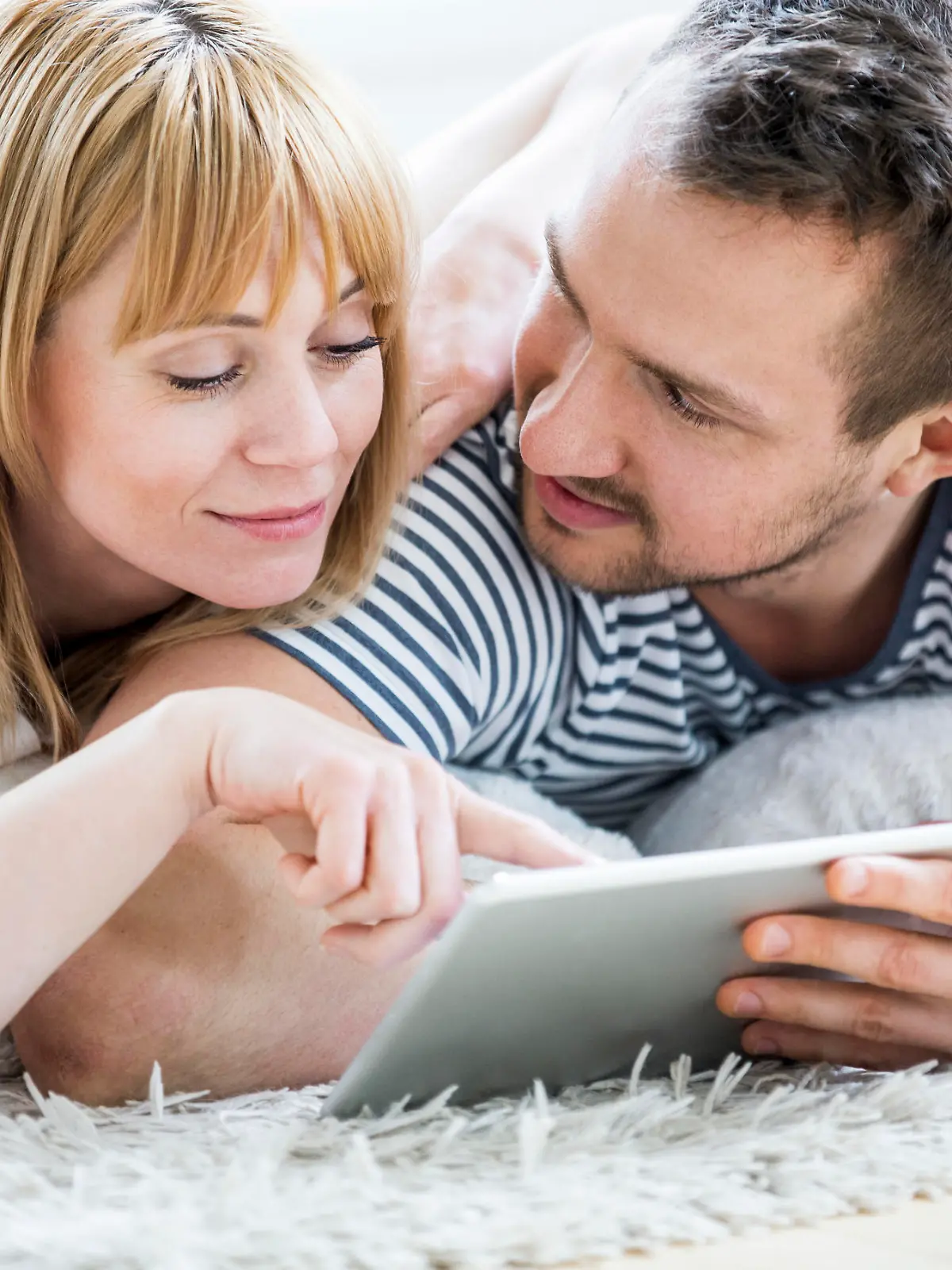 Couple with tablet lying on floor and surfing the net