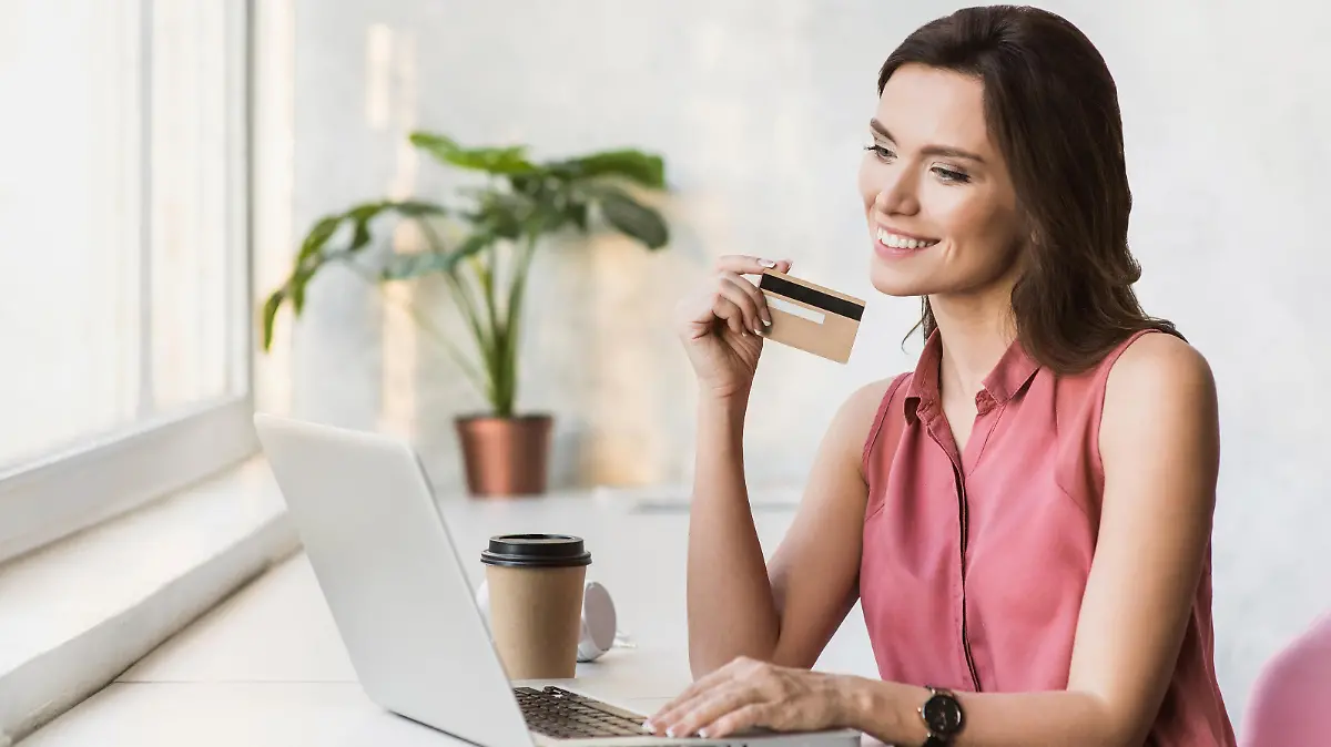 Frau sitzt an Laptop mit Amex Gold Card.