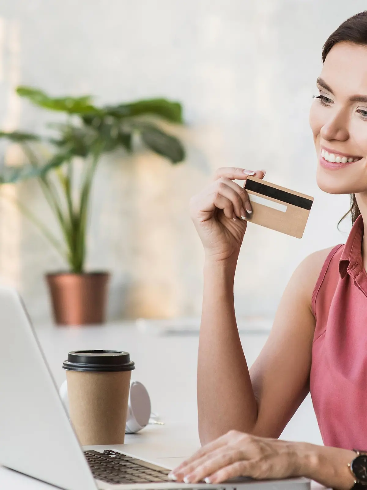 Frau sitzt an Laptop mit Amex Gold Card.