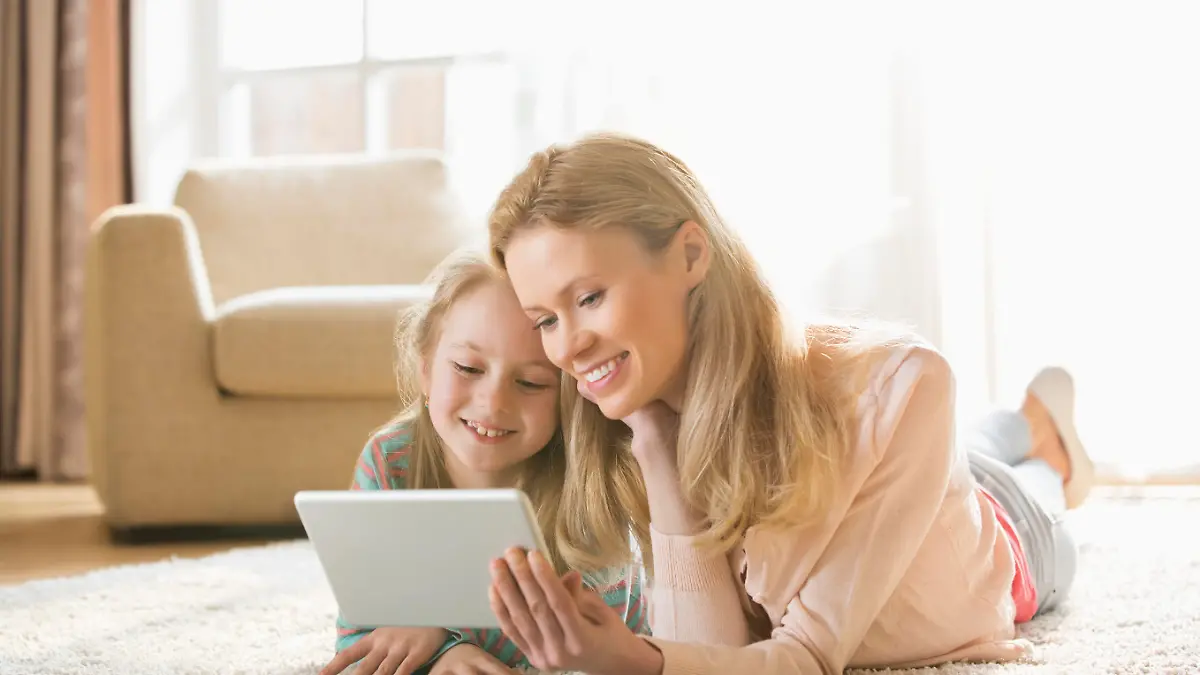 Mother and daughter using digital tablet on floor at home