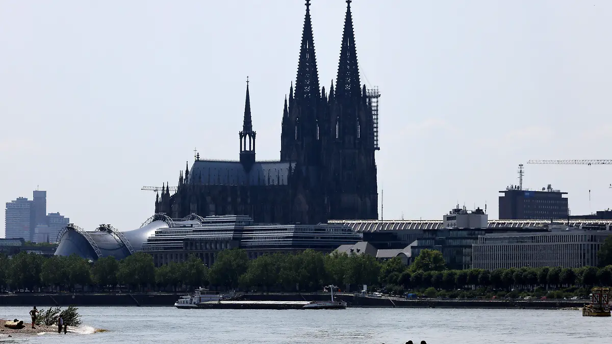 17.06.2021, Nordrhein-Westfalen, Köln: Menschen sitzen am Rheinufer im Schatten unter einer Brücke. Das Wetter in Nordrhein-Westfalen ist hochsommerlich. Foto: Oliver Berg/dpa +++ dpa-Bildfunk +++