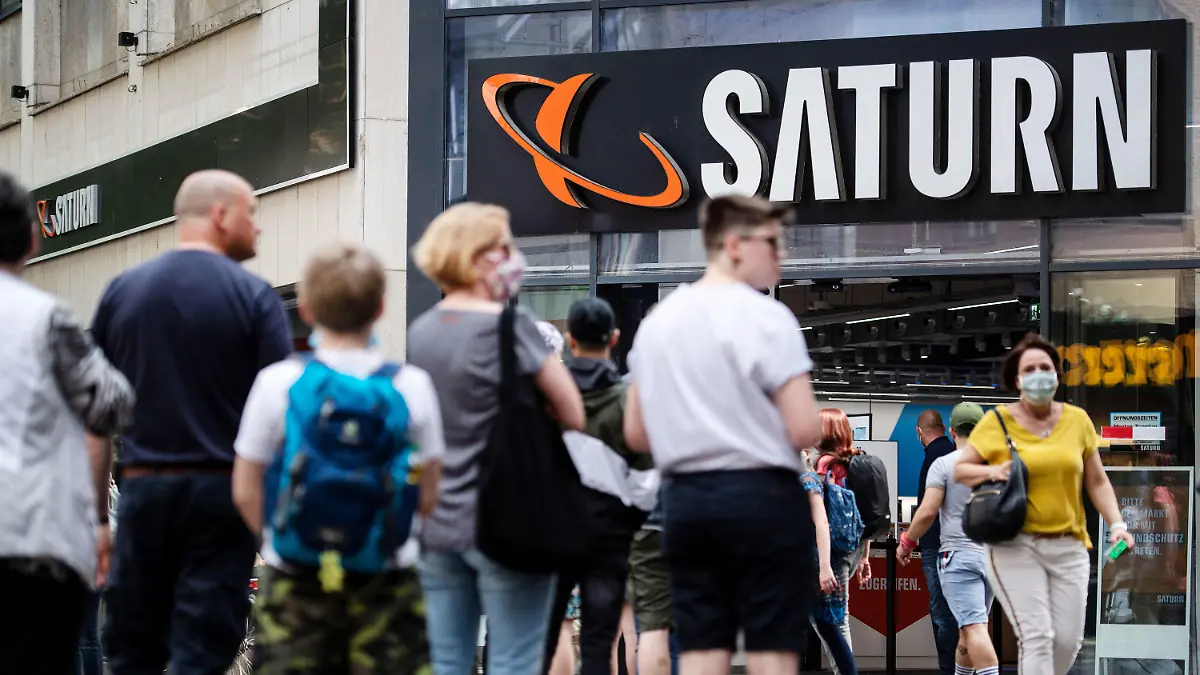 ARCHIV - 09.05.2020, Nordrhein-Westfalen, Köln: Menschen stehen in einer Warteschlange vor einer Filiale des Elektrohändlers Saturn an. Der Elektronikhändler Ceconomy hat wegen der Corona-Pandemie im zweiten Geschäftsquartal (bis Ende März) einen Nettoverlust von rund 309 Millionen Euro verbucht. Ceconomy hatte im Zuge der Corona-Krise den überwiegenden Teil seiner Geschäfte schließen müssen. Mittlerweile sind nahezu alle Läden wieder geöffnet. Für das Gesamtjahr 2019/20 (bis 30. September) erwartet der Konzern nun einem währungsbereinigten Umsatzrückgang. Foto: Marius Becker/dpa +++ dpa-Bildfunk +++