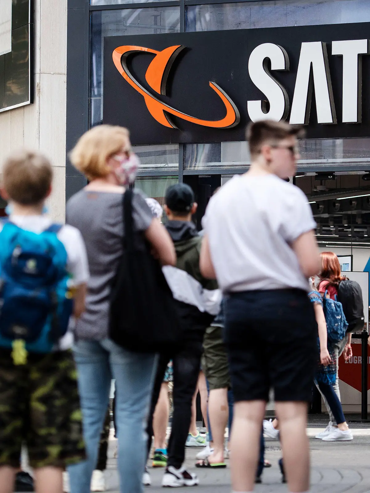 ARCHIV - 09.05.2020, Nordrhein-Westfalen, Köln: Menschen stehen in einer Warteschlange vor einer Filiale des Elektrohändlers Saturn an. Der Elektronikhändler Ceconomy hat wegen der Corona-Pandemie im zweiten Geschäftsquartal (bis Ende März) einen Nettoverlust von rund 309 Millionen Euro verbucht. Ceconomy hatte im Zuge der Corona-Krise den überwiegenden Teil seiner Geschäfte schließen müssen. Mittlerweile sind nahezu alle Läden wieder geöffnet. Für das Gesamtjahr 2019/20 (bis 30. September) erwartet der Konzern nun einem währungsbereinigten Umsatzrückgang. Foto: Marius Becker/dpa +++ dpa-Bildfunk +++
