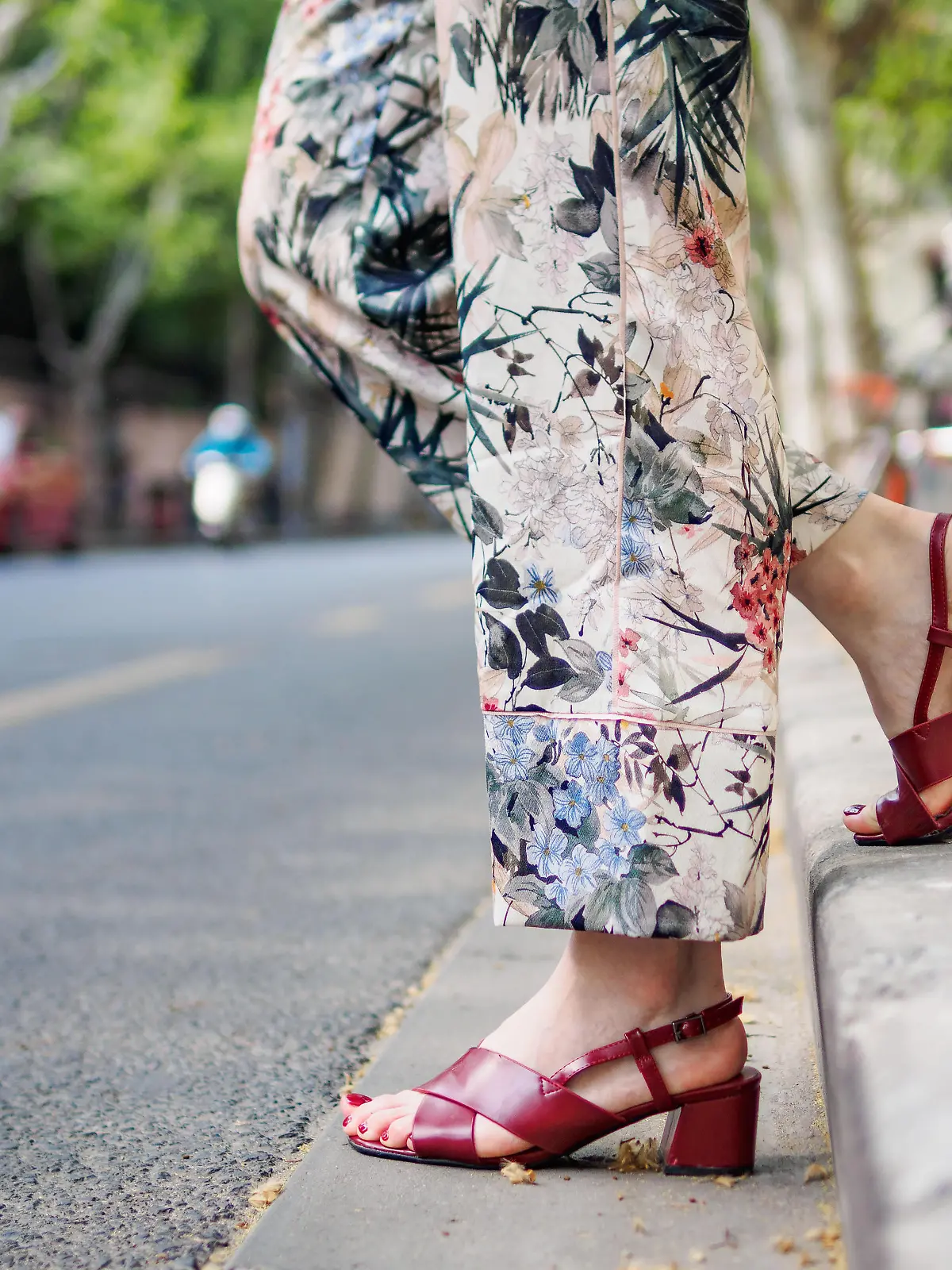 Close up on girl's feet wearing red sandals in the city, urban road background.