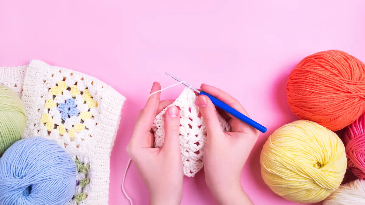 Closeup background of crochet knitting in progress and multicolored yarn balls.
