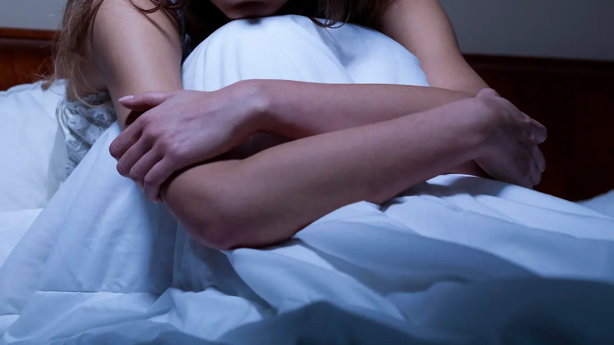 Young worried woman sitting in bed at night