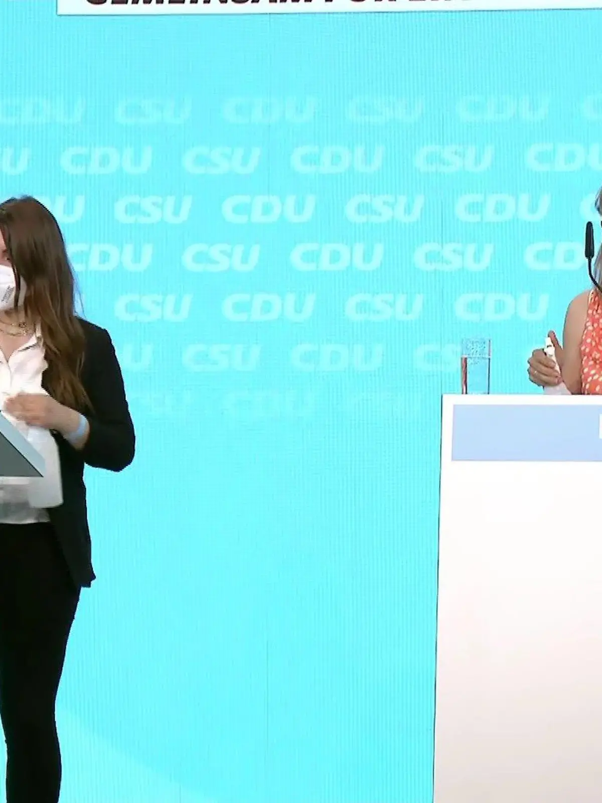 Zwei Frauen desinfizieren Rednerpulte