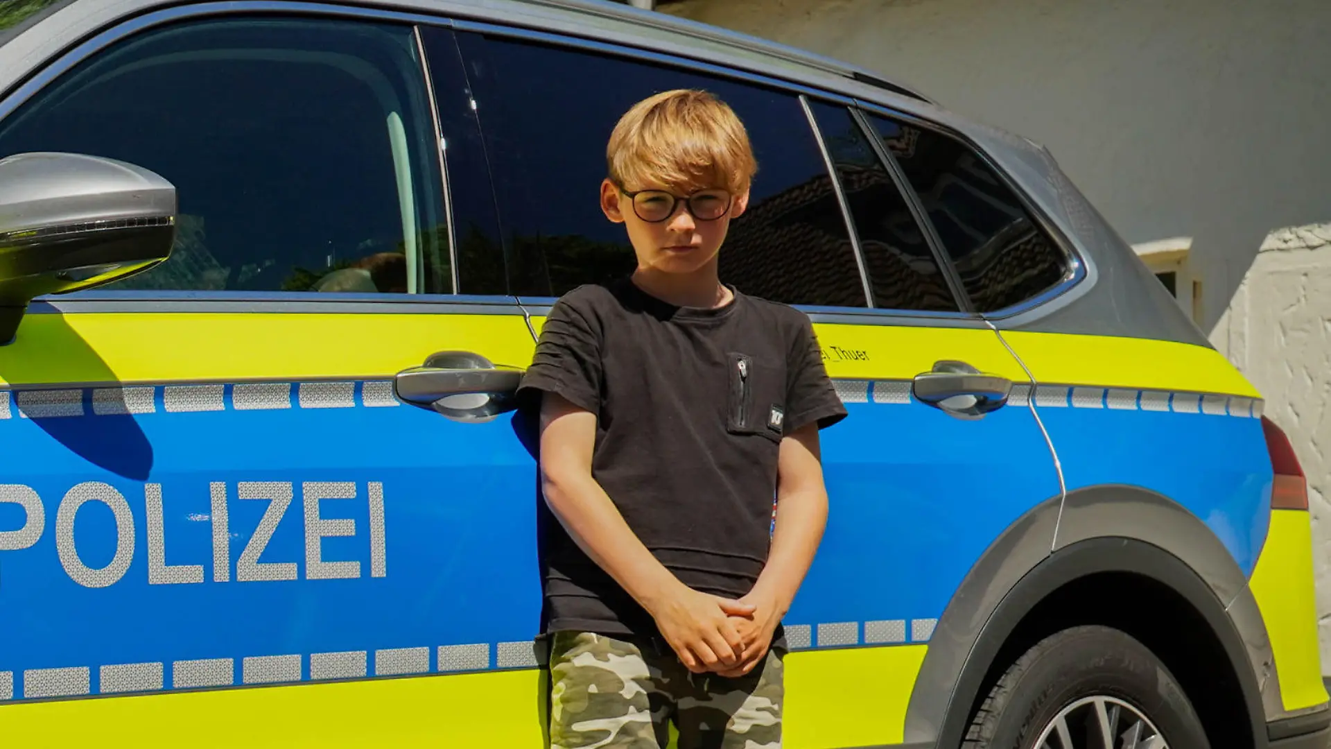 Lennard steht vor einem Polizeiauto