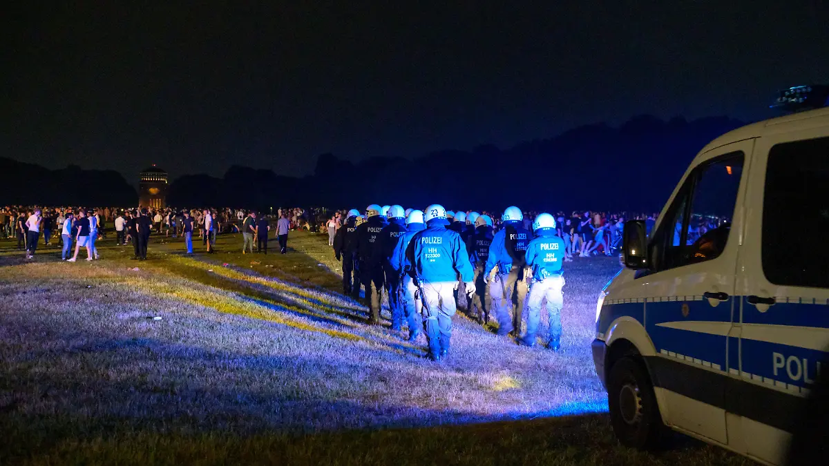 18.06.2021, Hamburg: Behelmte Polizisten laufen begleitet von einem Mannschaftswagen in Richtung der Menschen auf der Stadtpark-Wiese. Die Polizei hat eine Party mit rund 3000 Menschen im Hamburger Stadtpark aufgelöst. (zu dpa: «Polizei räumt Party von 3000 Menschen im Hamburger Stadtpark») Foto: Jonas Walzberg/dpa - ACHTUNG: Verwendung nur im vollen Format +++ dpa-Bildfunk +++