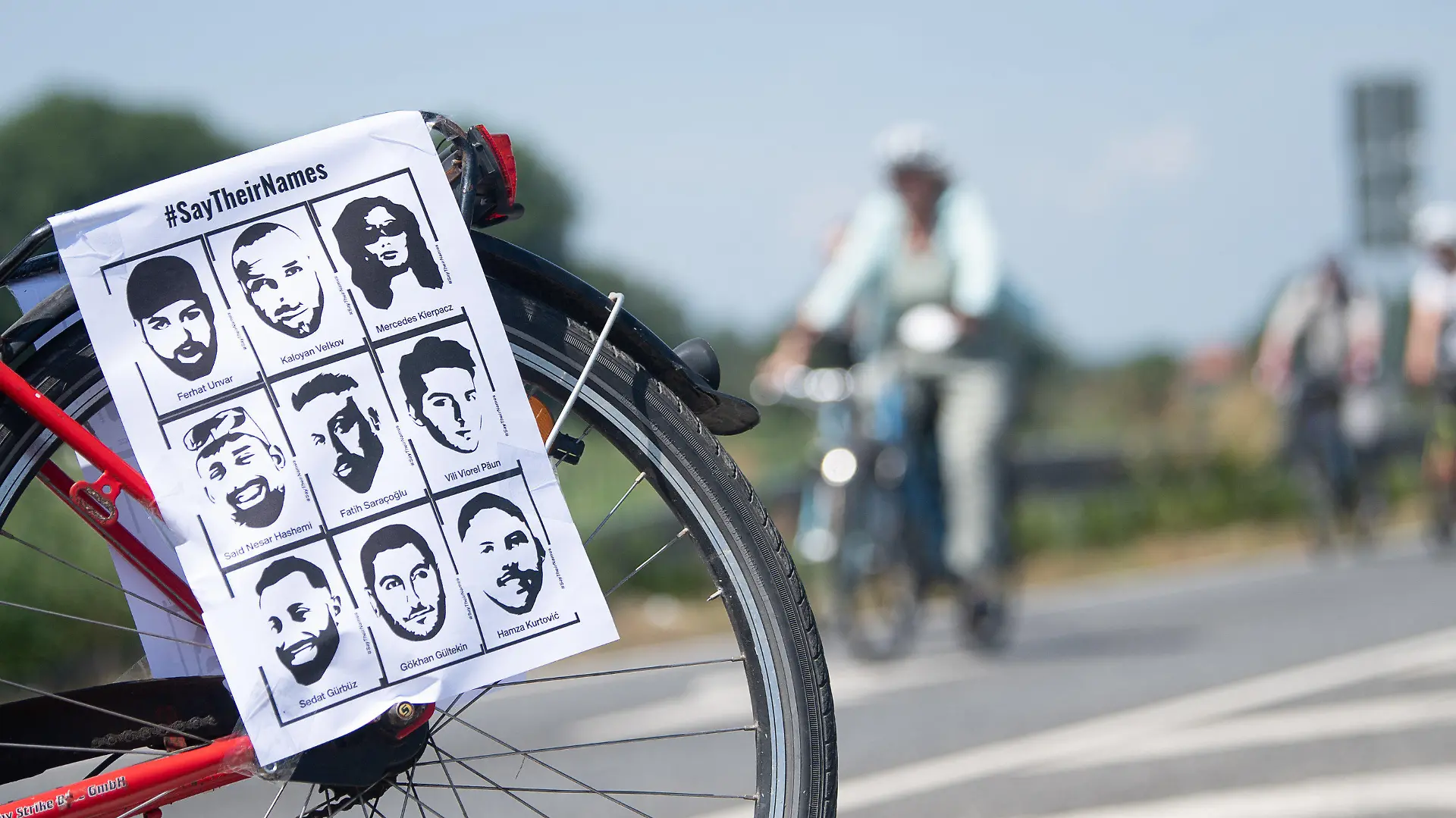 19.06.2021, Hessen, Maintal: Ein Fahrrad mit dem Konterfei der Opfer steht während der Fahrradsternfahrt «Stern für Hanau» zur Erinnerung an den rechtsterroristischen Anschlag vor den Teilnehmenden. An dem «Ride to Remember» beteiligen sich Radfahrer aus vielen Gemeinden und Städten Hessens sowie aus Nordbayern. Foto: Sebastian Gollnow/dpa +++ dpa-Bildfunk +++