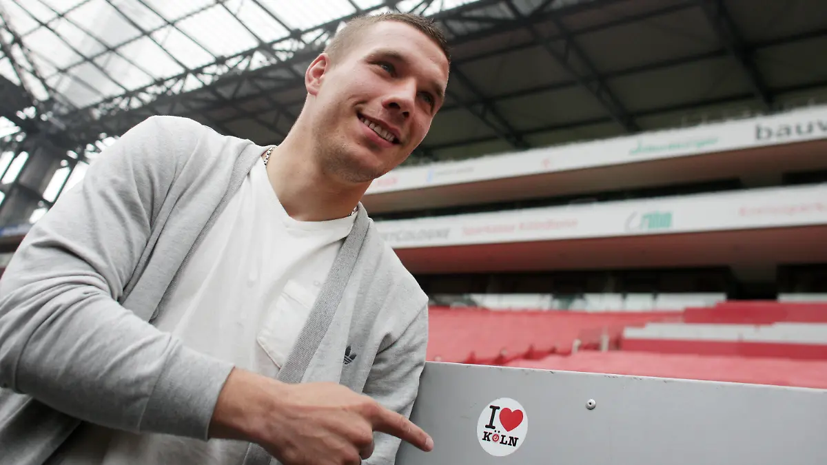 ARCHIV - 02.05.2012, Nordrhein-Westfalen, Köln: Fußball-Nationalspieler Lukas Podolski vom 1. FC Köln zeigt im RheinEnergieStadion auf einen Aufkleber «I love Köln». Podolski ist nach seinem Japan-Abenteuer zurück in der Heimat und steht vor Gesprächen mit dem 1. FC Köln. Foto: Rolf Vennenbernd/dpa +++ dpa-Bildfunk +++