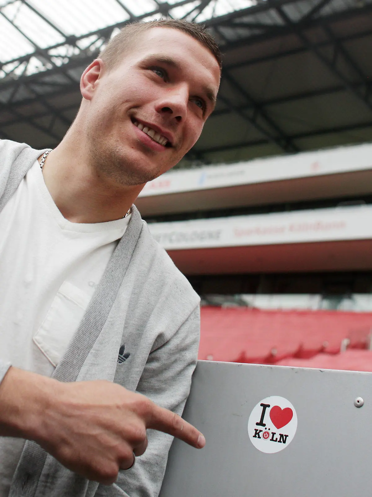 ARCHIV - 02.05.2012, Nordrhein-Westfalen, Köln: Fußball-Nationalspieler Lukas Podolski vom 1. FC Köln zeigt im RheinEnergieStadion auf einen Aufkleber «I love Köln». Podolski ist nach seinem Japan-Abenteuer zurück in der Heimat und steht vor Gesprächen mit dem 1. FC Köln. Foto: Rolf Vennenbernd/dpa +++ dpa-Bildfunk +++