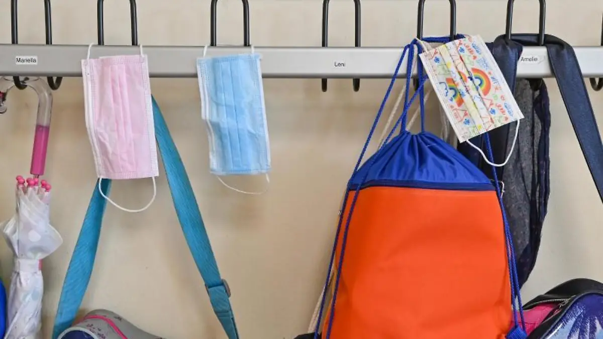 Masken hängen zusammen mit Taschen und Rucksäcken an Kleiderhaken